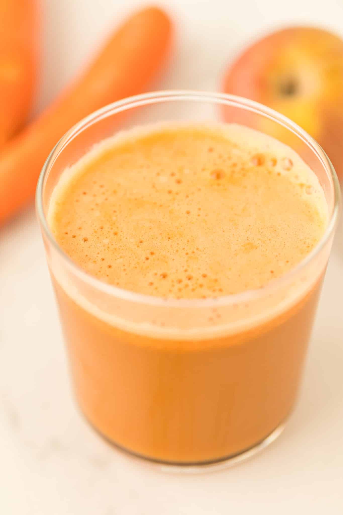 carrot and cucumber juice in a pretty glass on table.