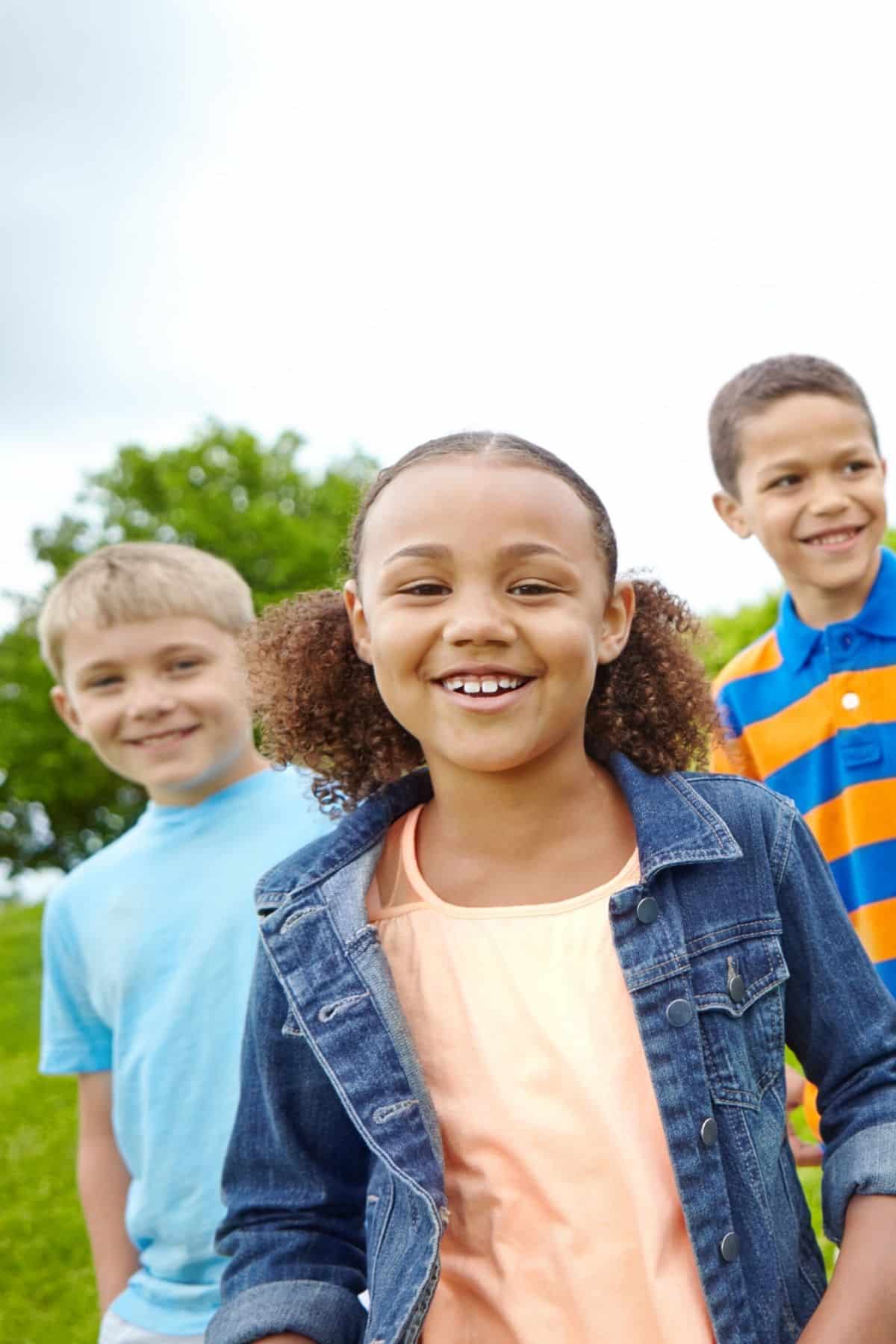 three smiling children at a park