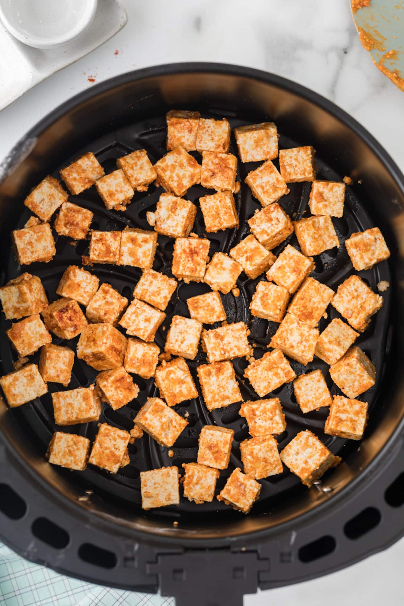 air fried tofu in air fryer basket.