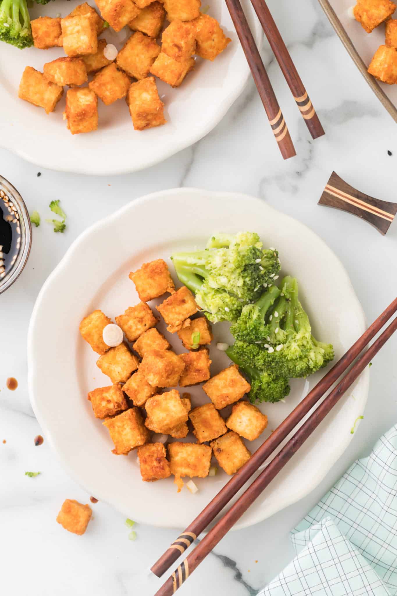 two plates of air fryer tofu served with broccoli.