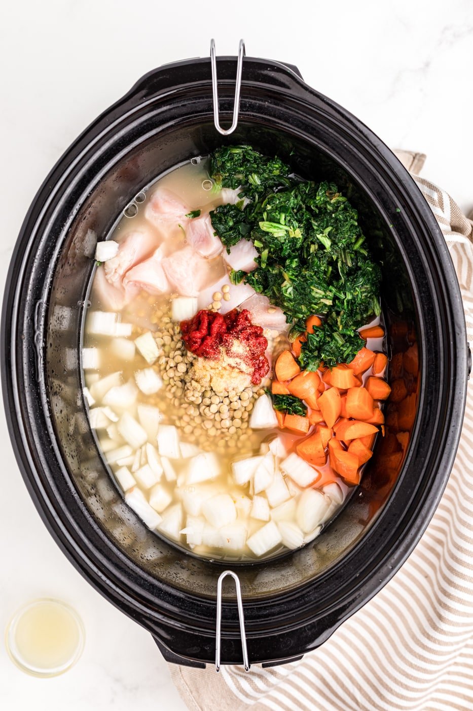 a slow cooker full of chicken, lentils, and veggies.