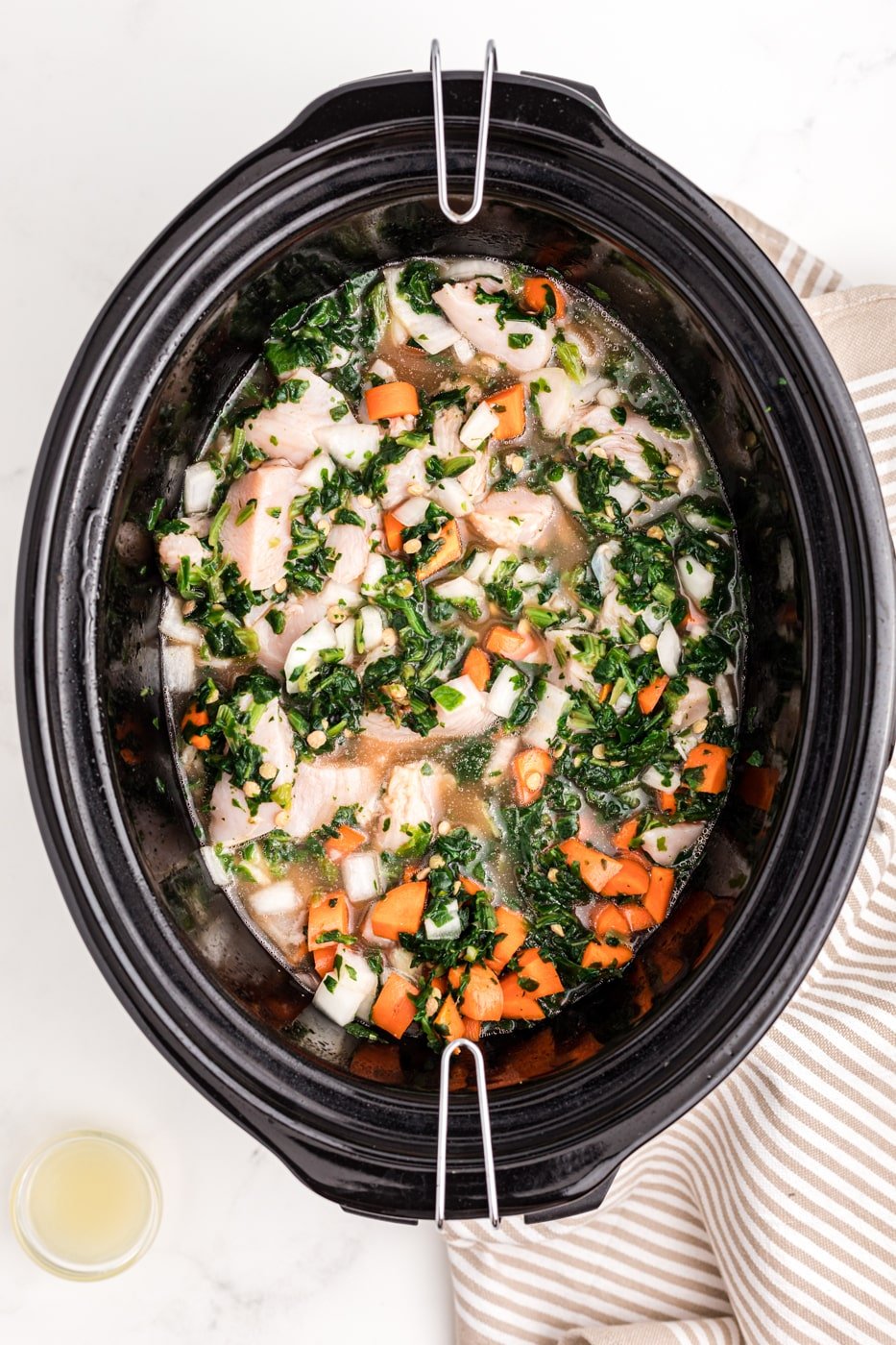 a crockpot with chicken, lentils, and veggies.