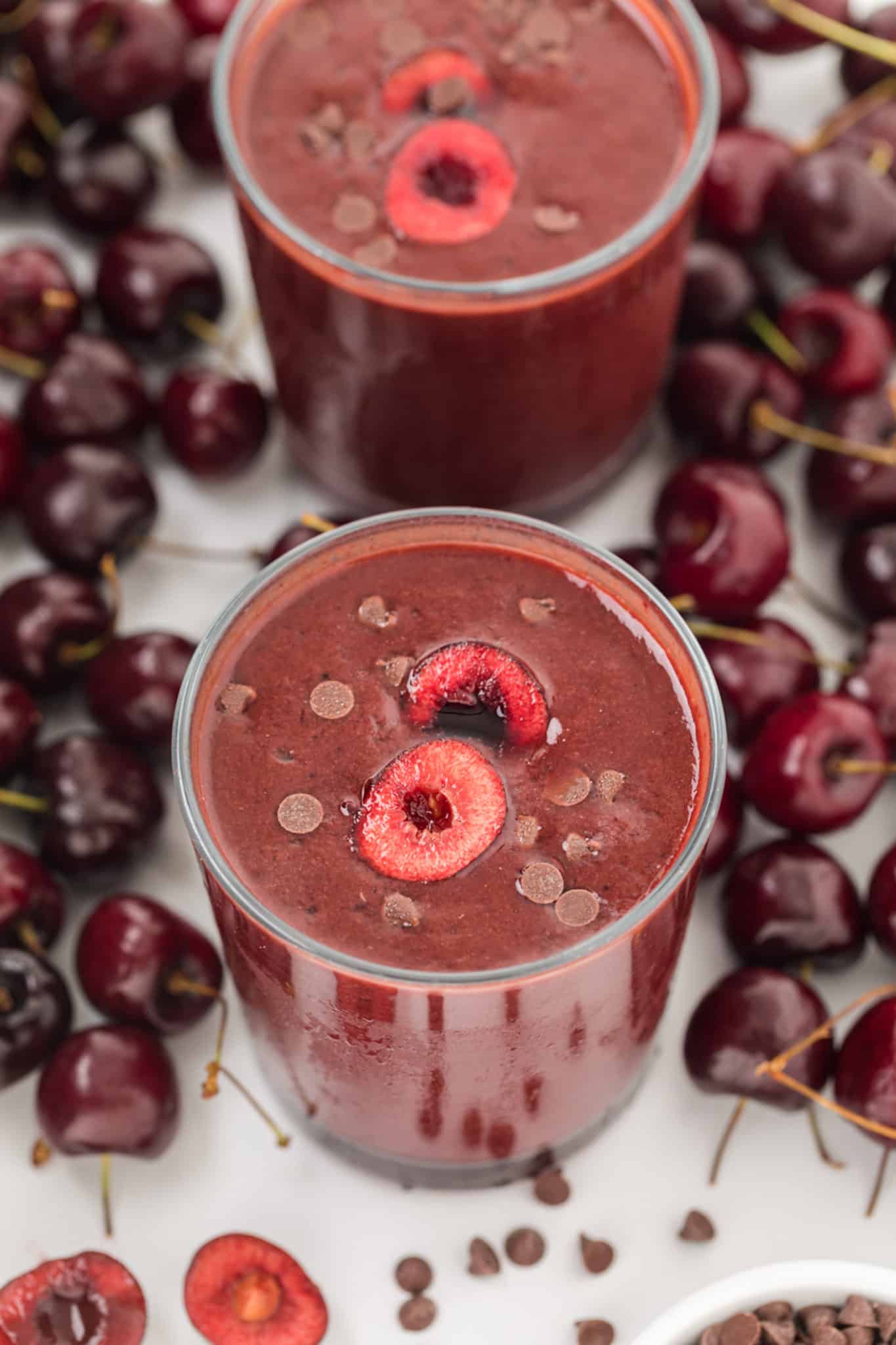 thick cherry smoothies on a table with fresh cherries