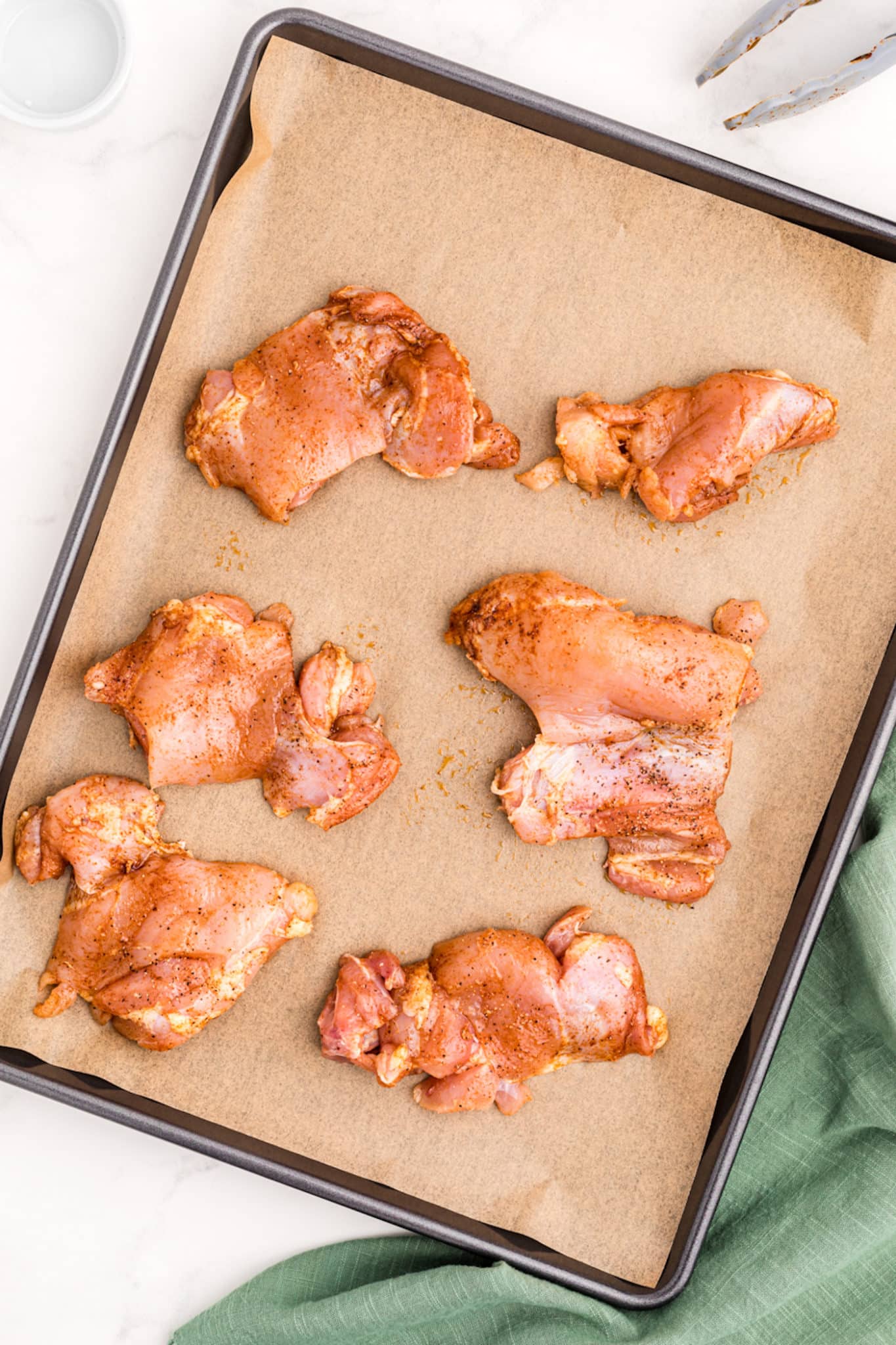 chicken thighs on a baking sheet with parchment paper