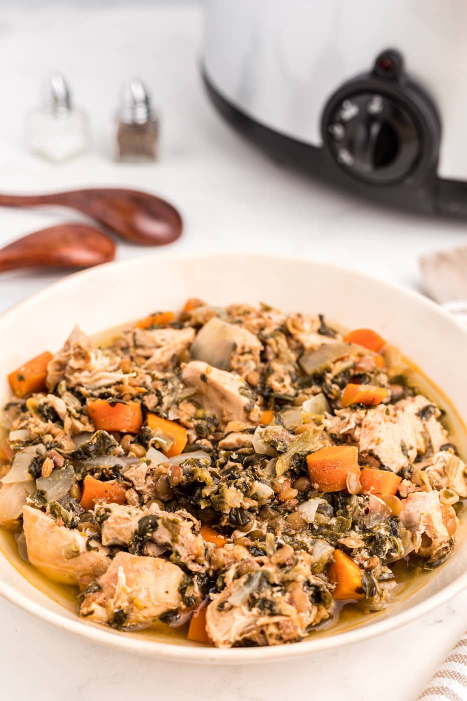 crockpot chicken stew with lentils and spinach in bowl.