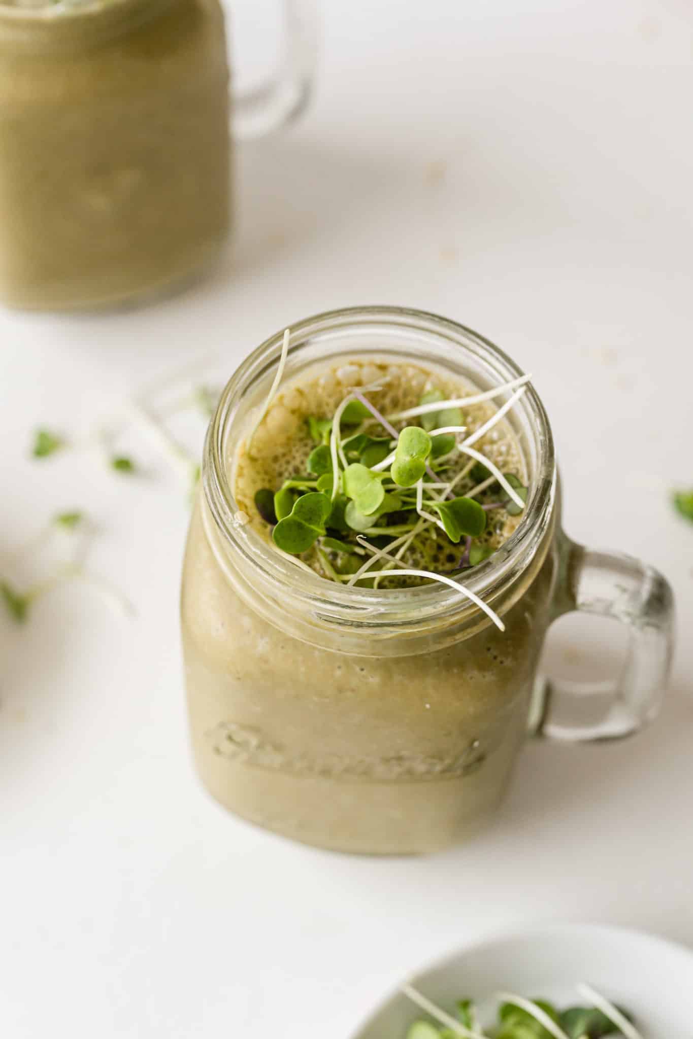 green smoothie topped with broccoli sprouts.