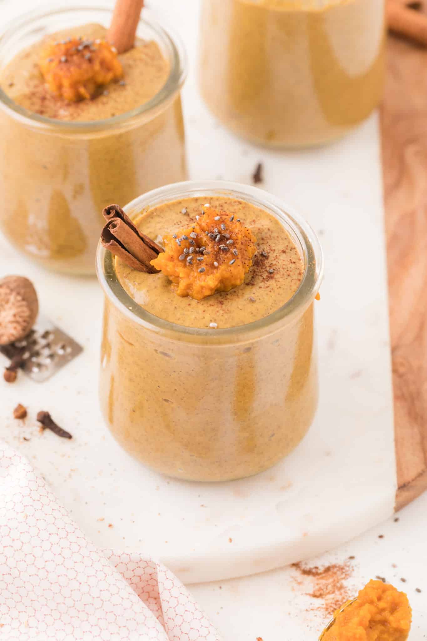 two jars of pumpkin chia seed pudding on a table.