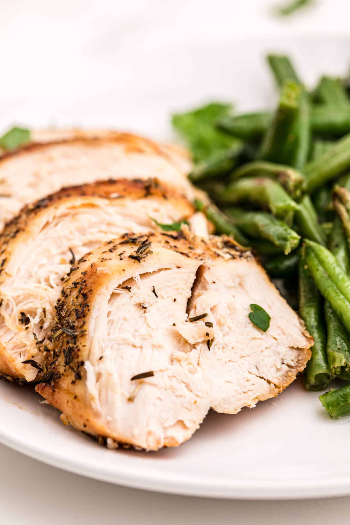 sliced air fryer turkey breast with green beans.