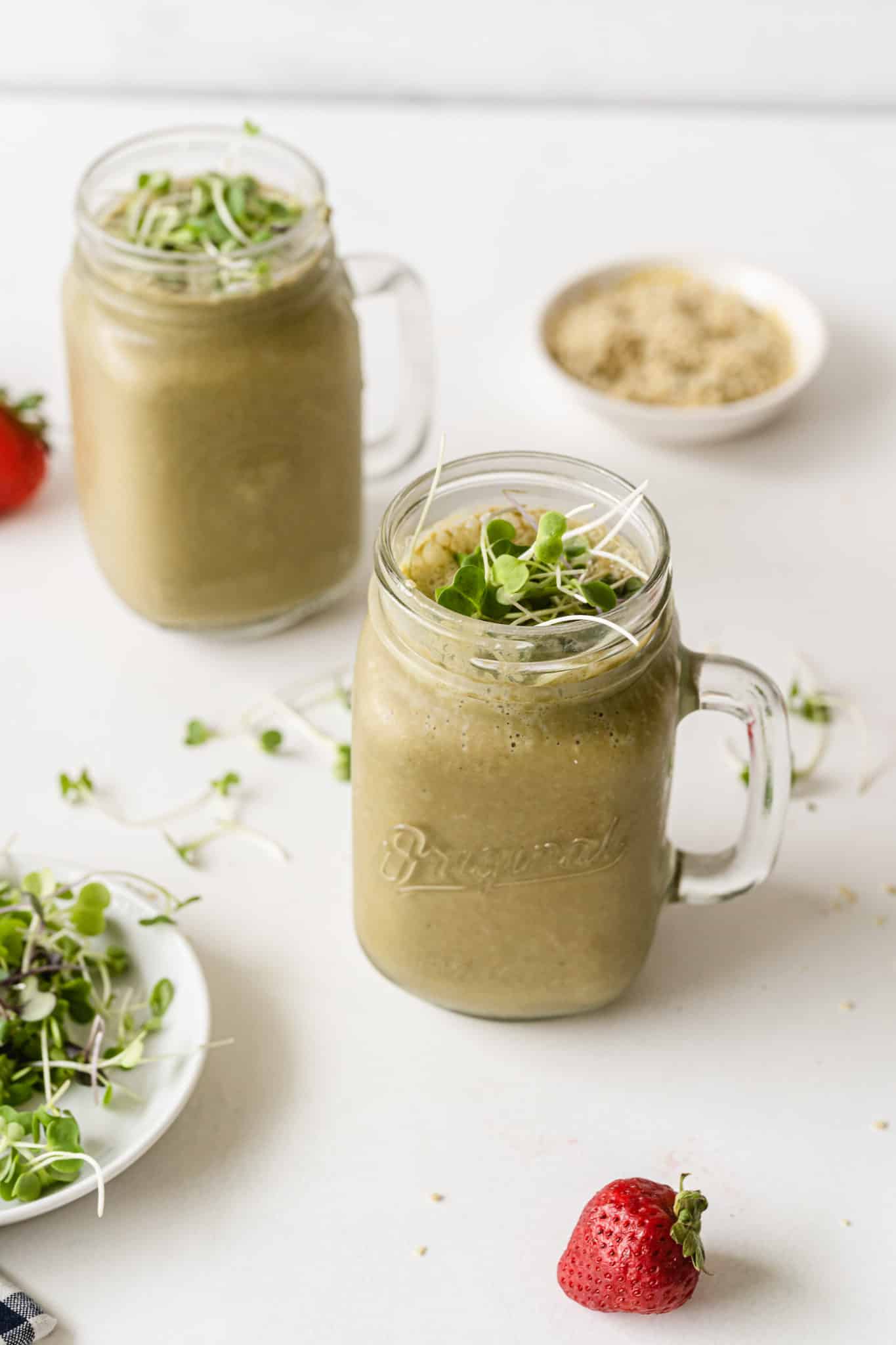 two glasses of broccoli sprout smoothie on a table.