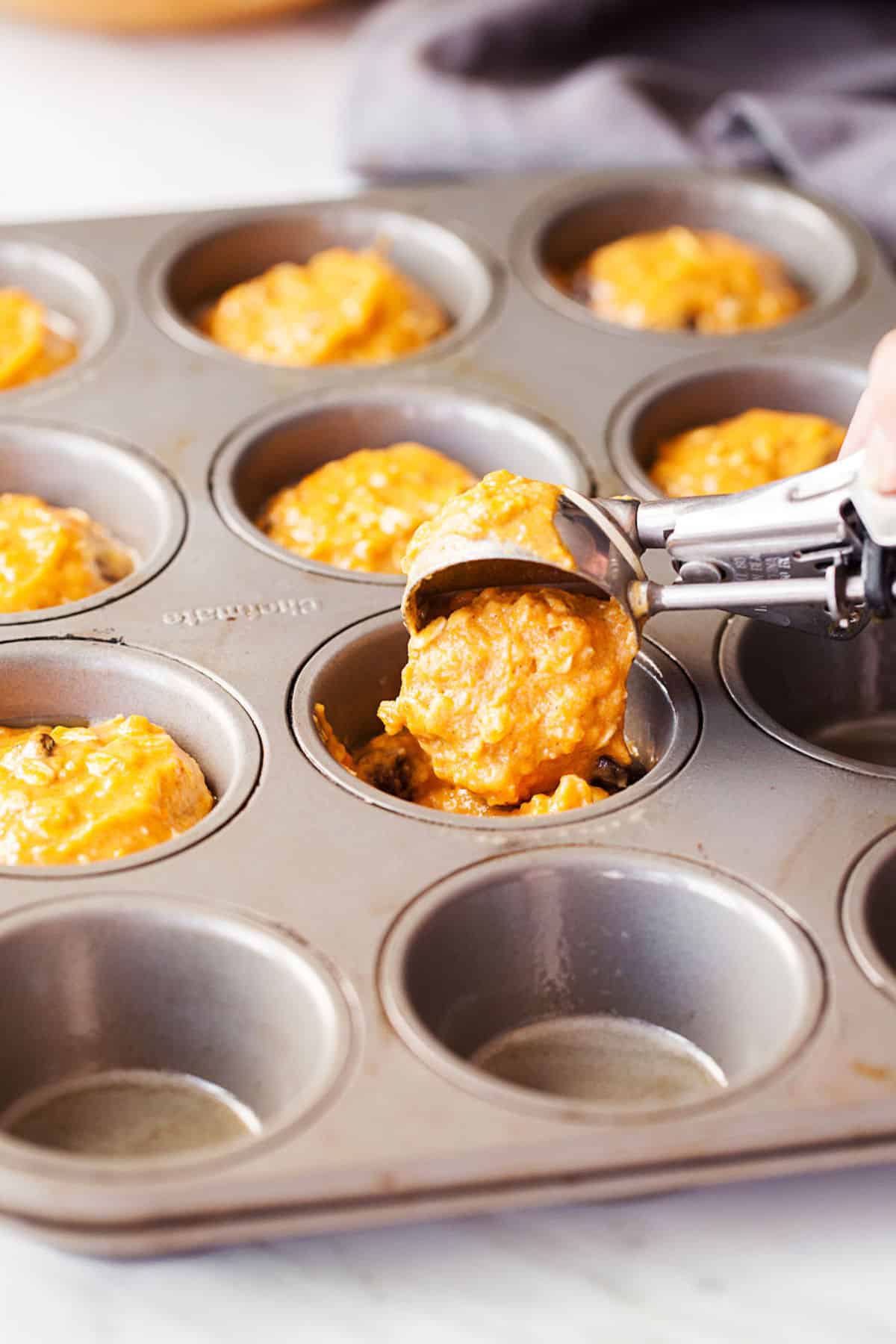 pouring muffin batter in muffin tin