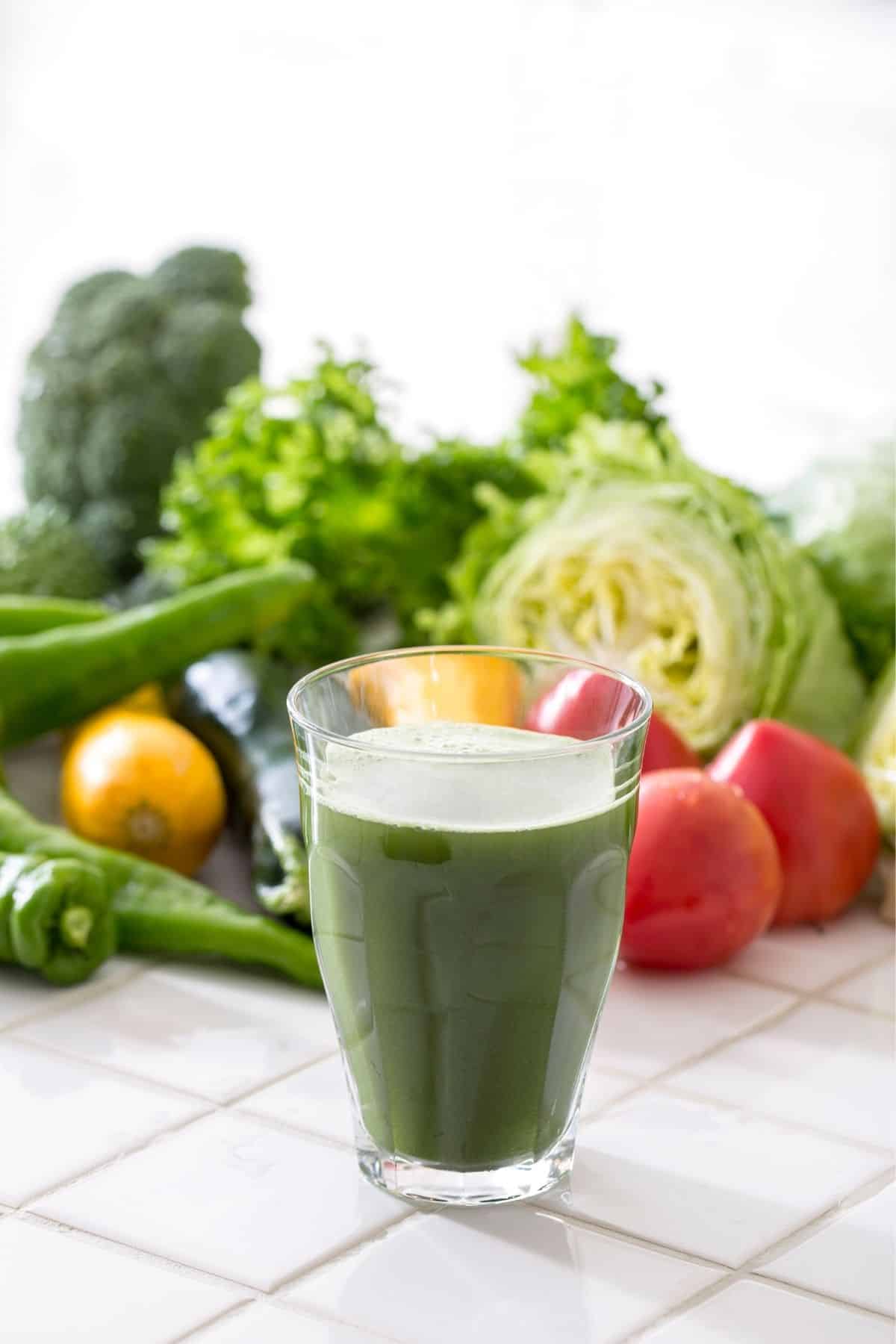 green juice on a table with fresh vegetables.