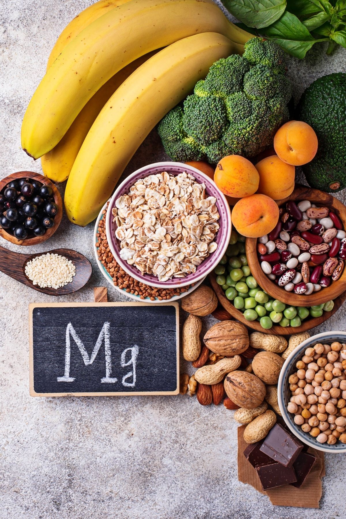 magnesium rich foods on a table with a chalkboard that has Mg on it.