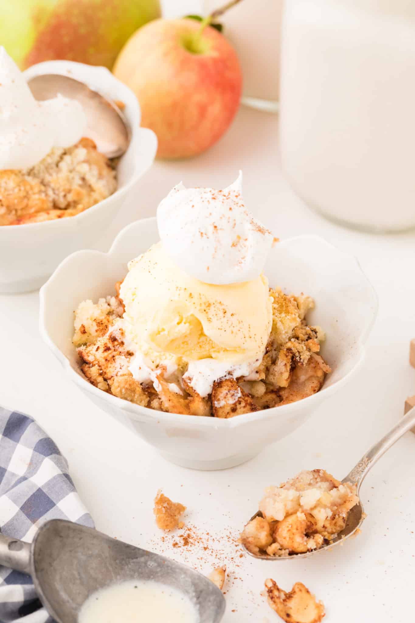 two bowls of air fryer apple crisp topped with ice cream.