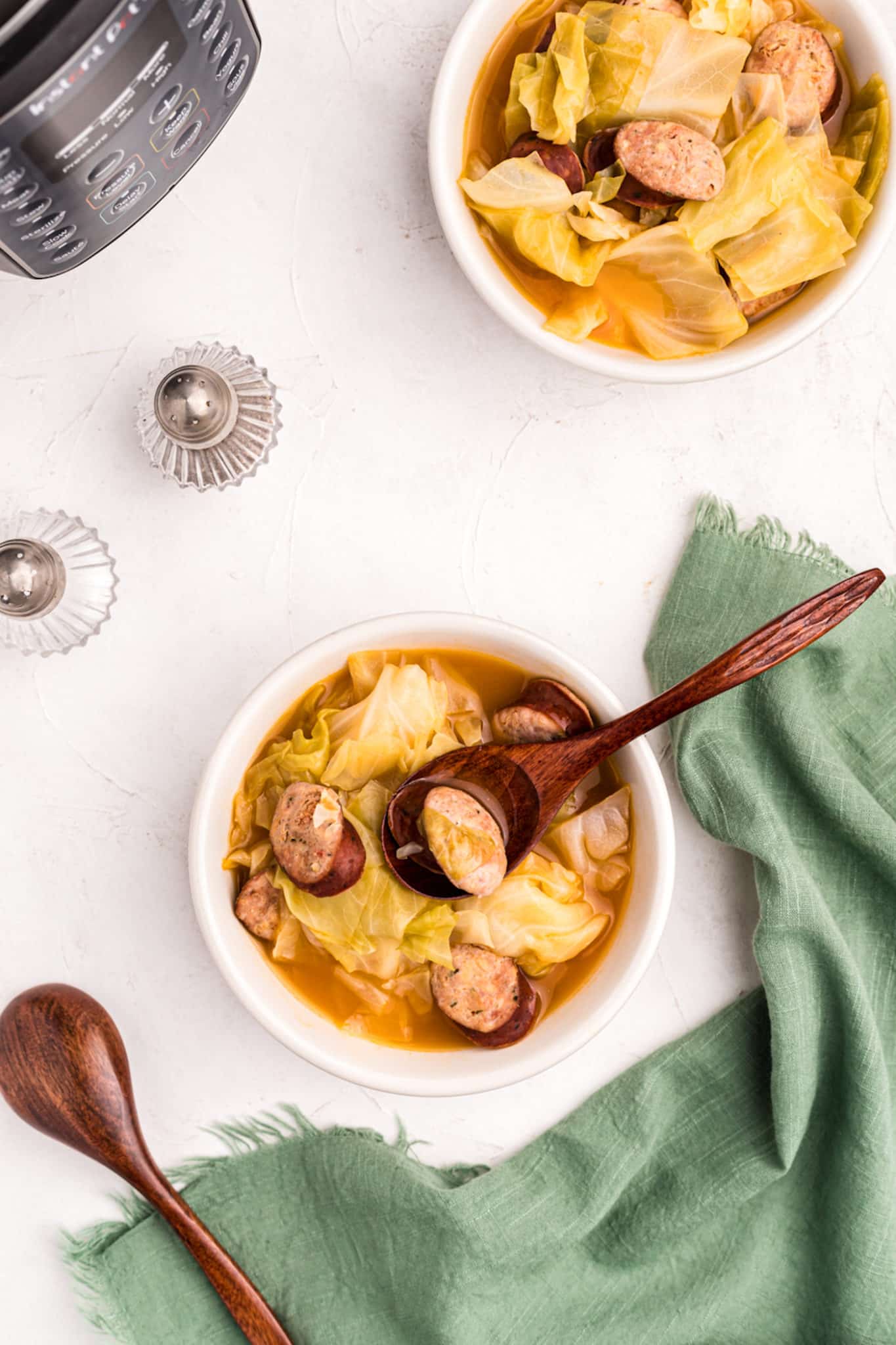 instant pot pressure cooker cabbage and sausage soup served in white bowls.