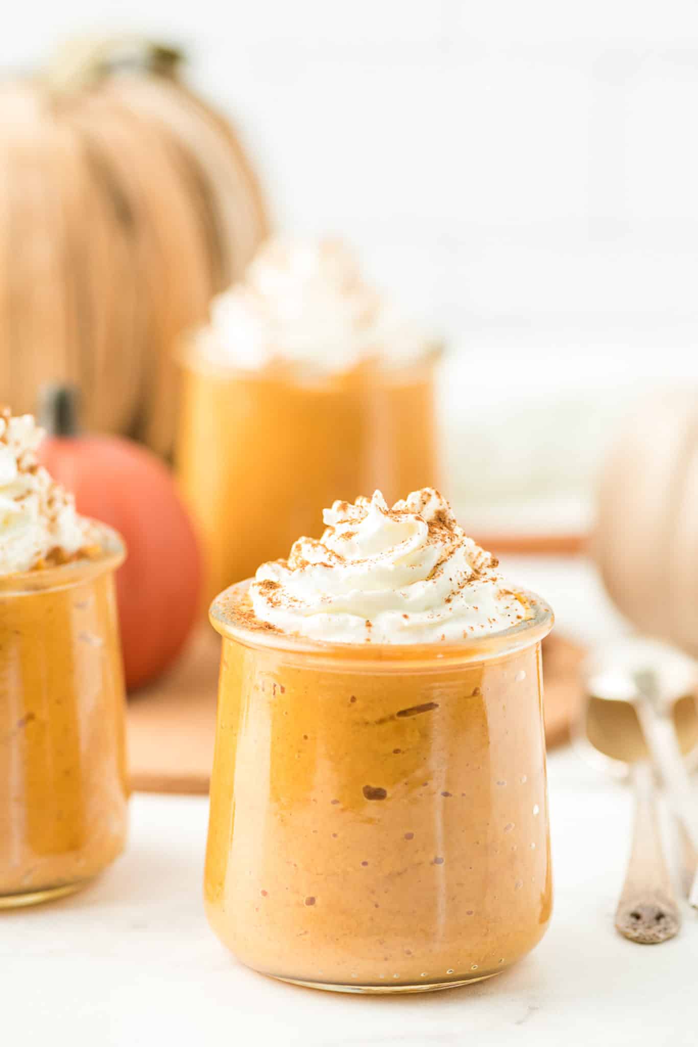 jars of pumpkin pudding with whipped topping ready to eat.