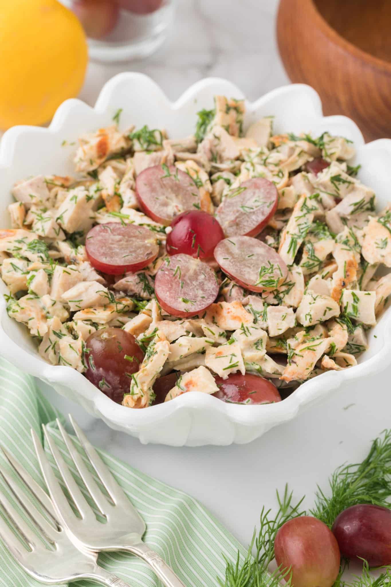 chicken salad with dill and grapes in a pretty white bowl with scalloped edges.