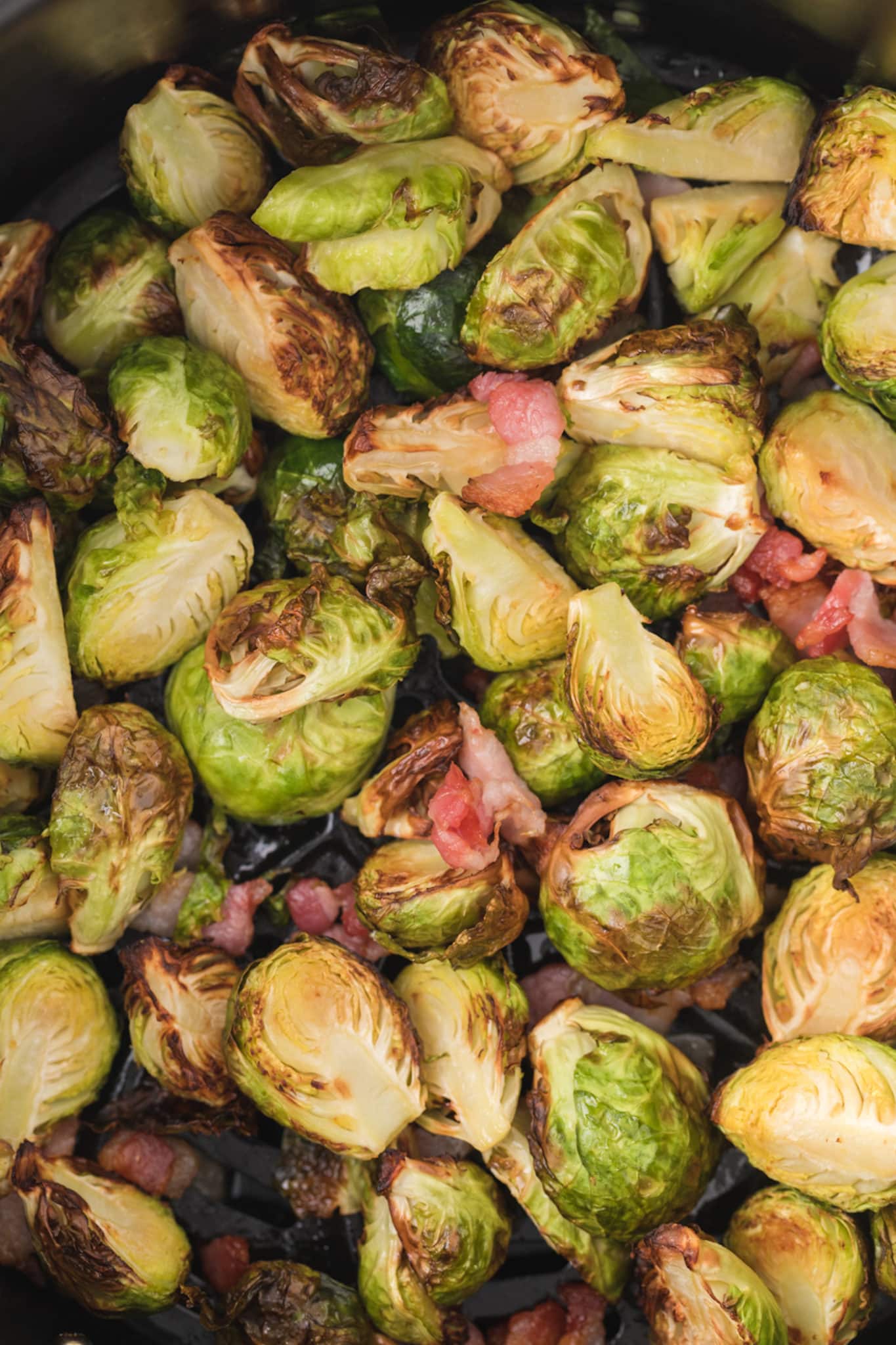 up close picture of cooked sprouts and bacon inside air fryer