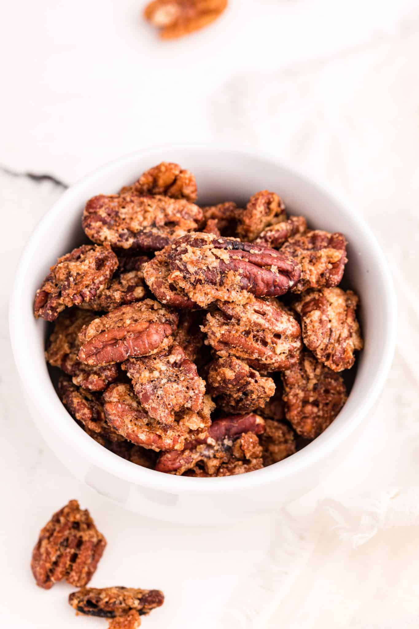 air fryer candied pecans in a white bowl on a table.