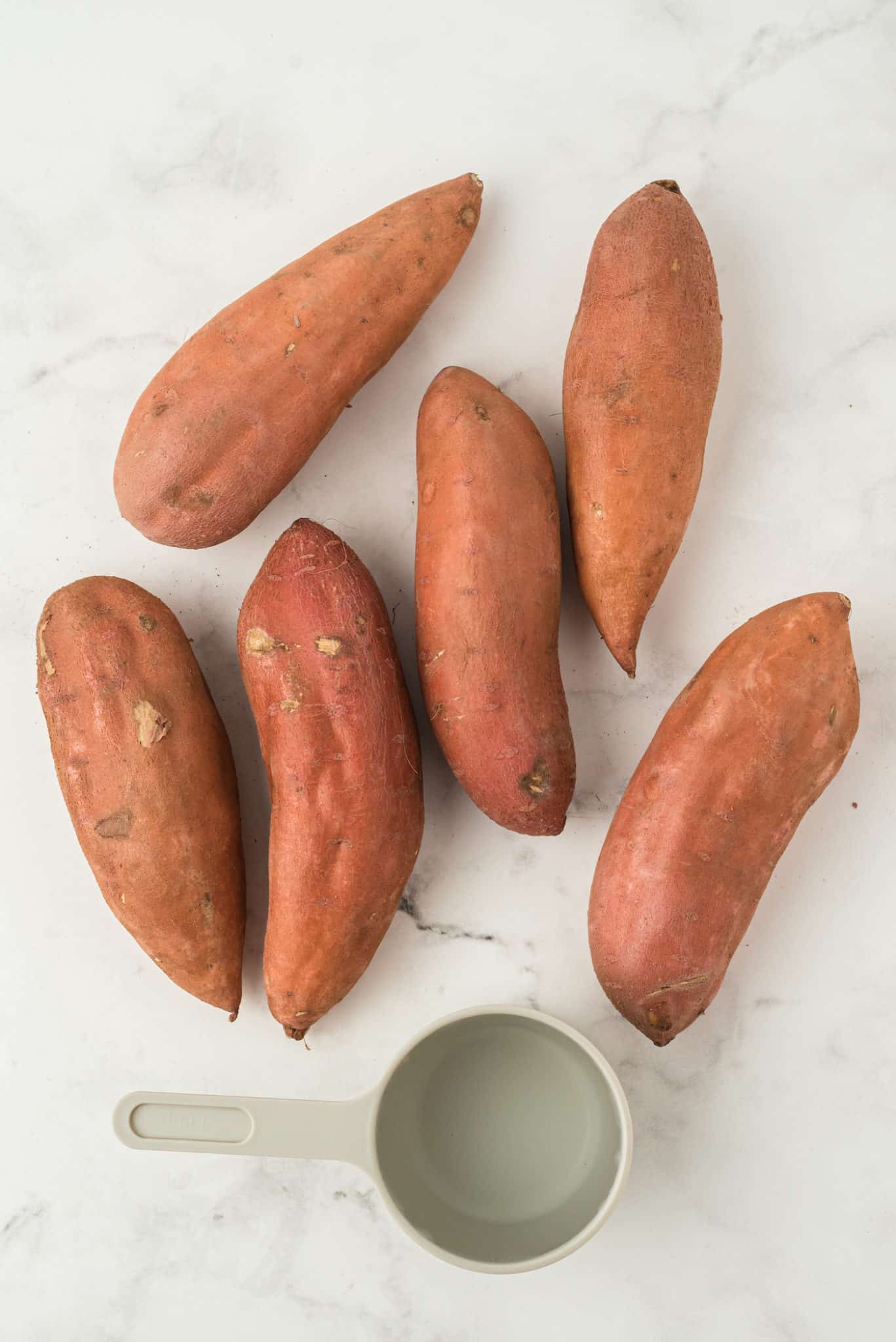 uncooked sweet potatoes and water on a tabletop.