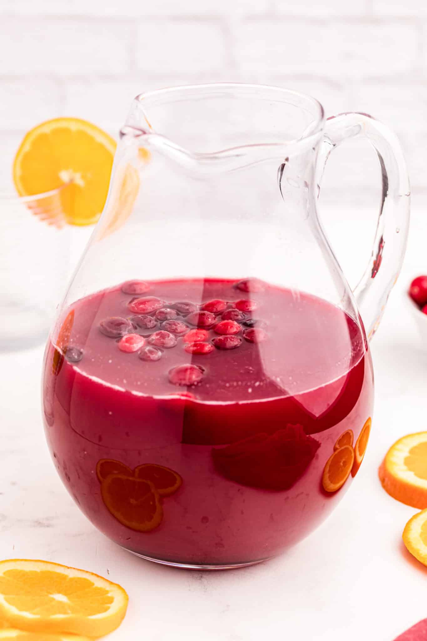 a pitcher of holiday brunch punch with fresh cranberries on top.