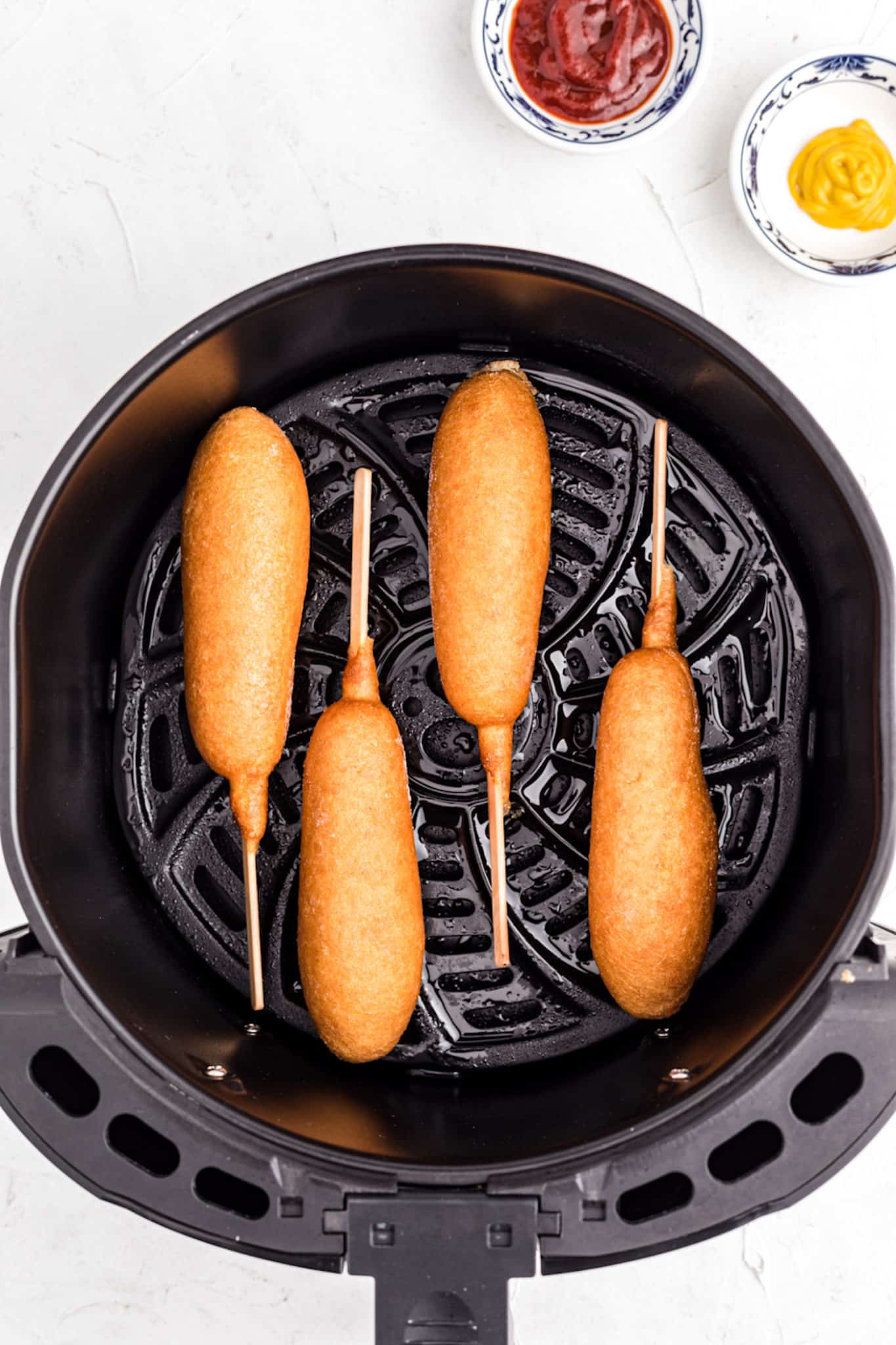 an air fryer with corn dogs in it.