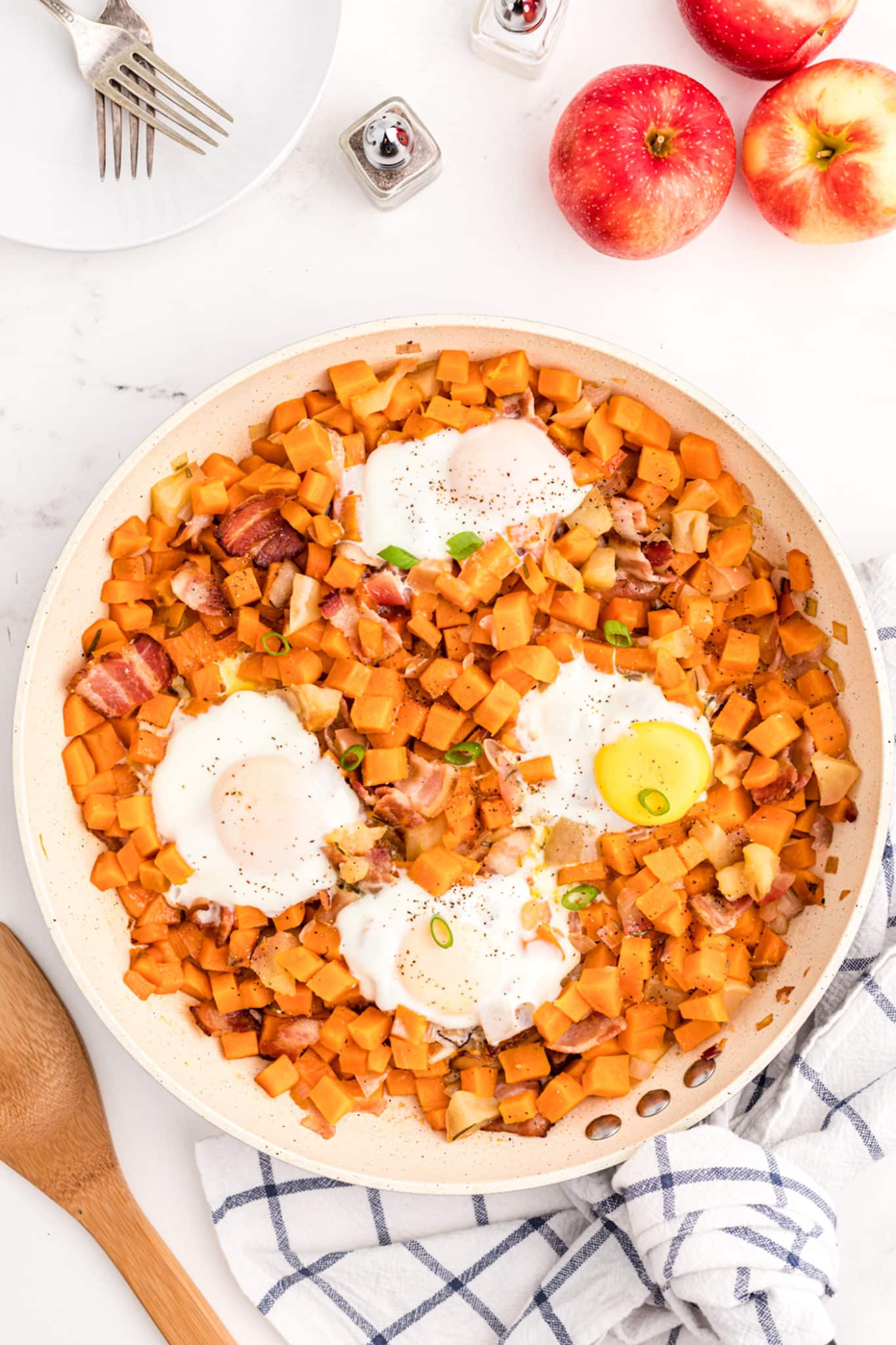 fried eggs on top of sweet potato hash in skillet