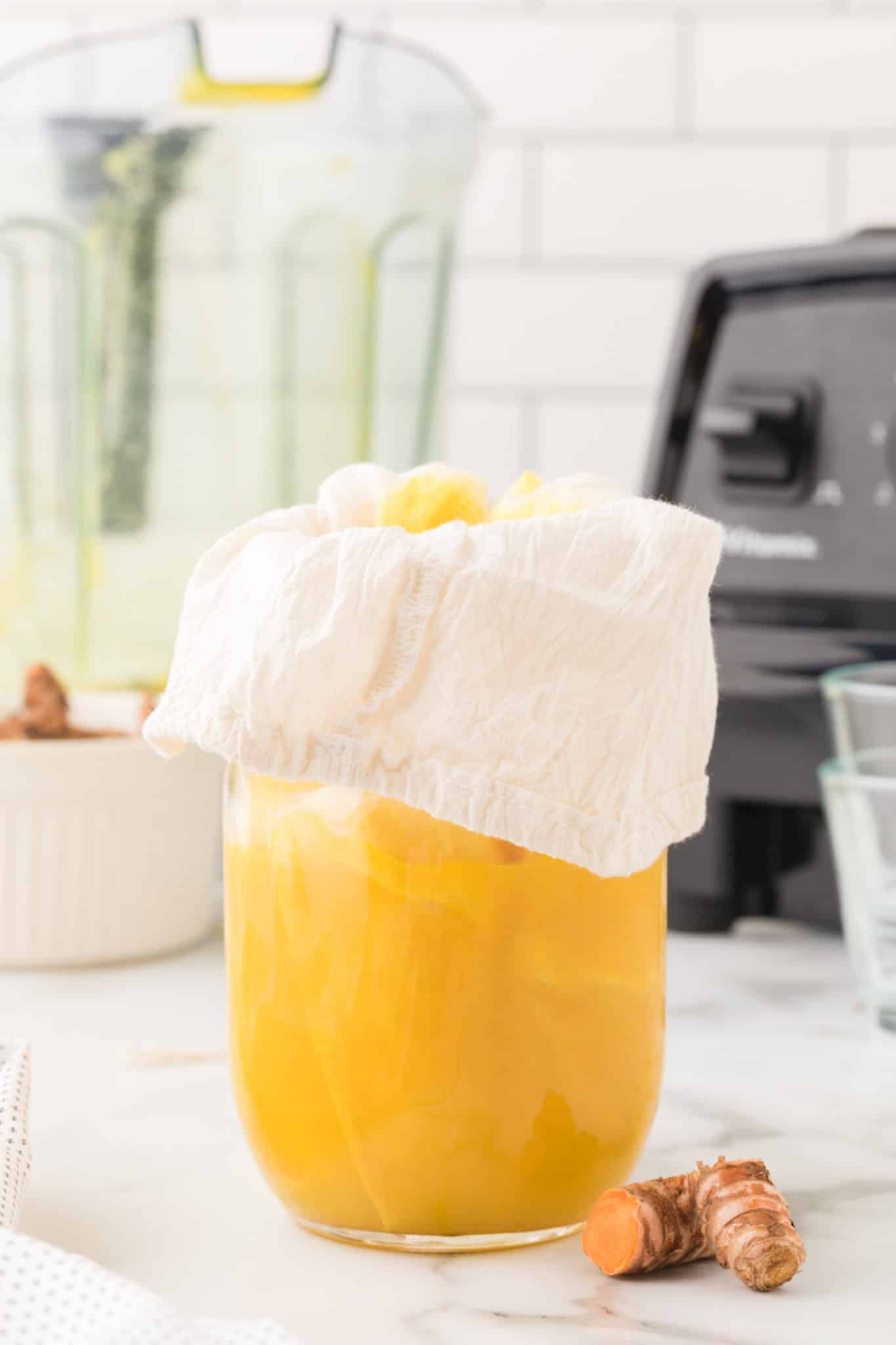straining turmeric shot with cheesecloth.
