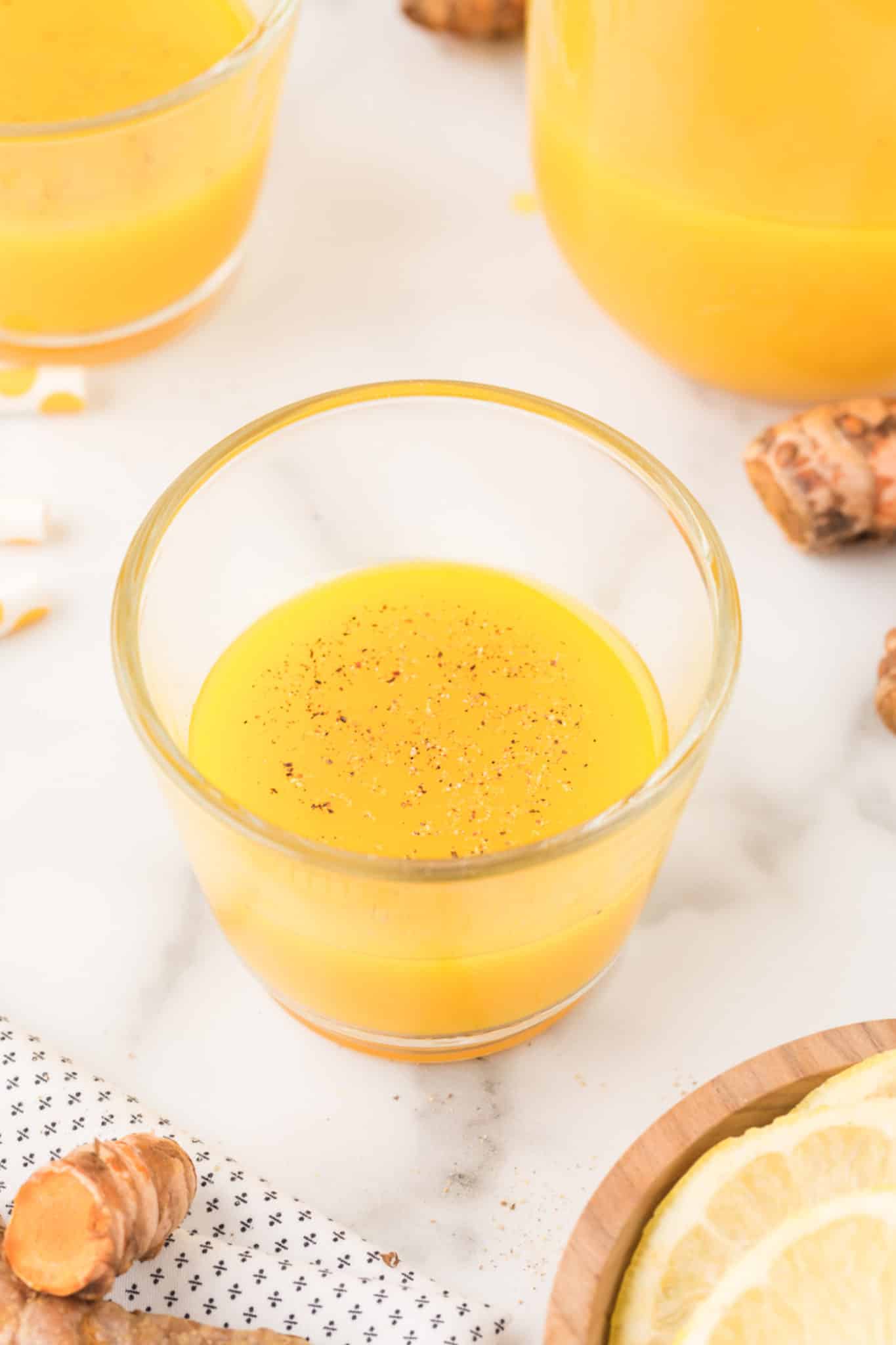 turmeric shot in a glass with ground black pepper on top.
