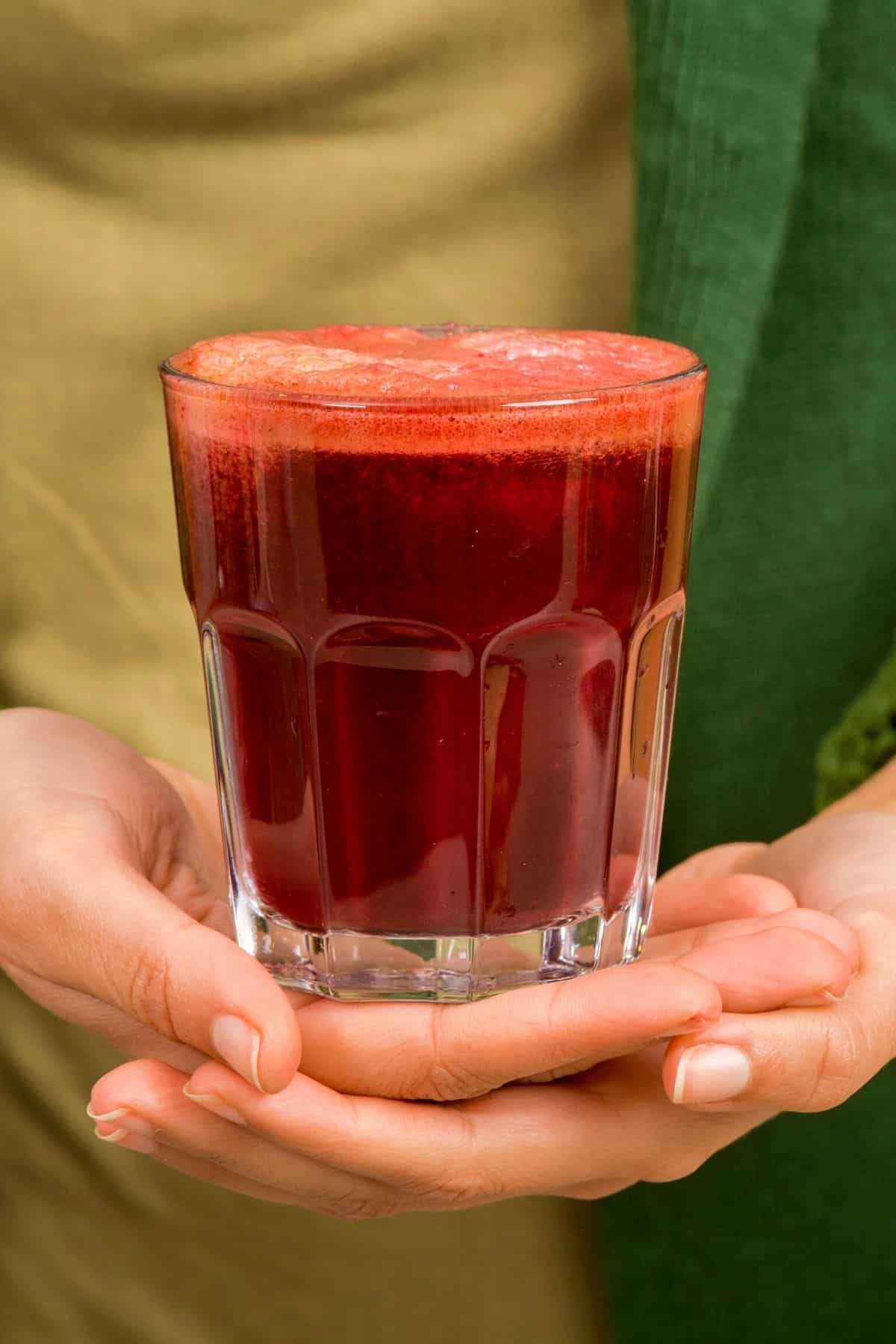 woman holding glass of beet juice.