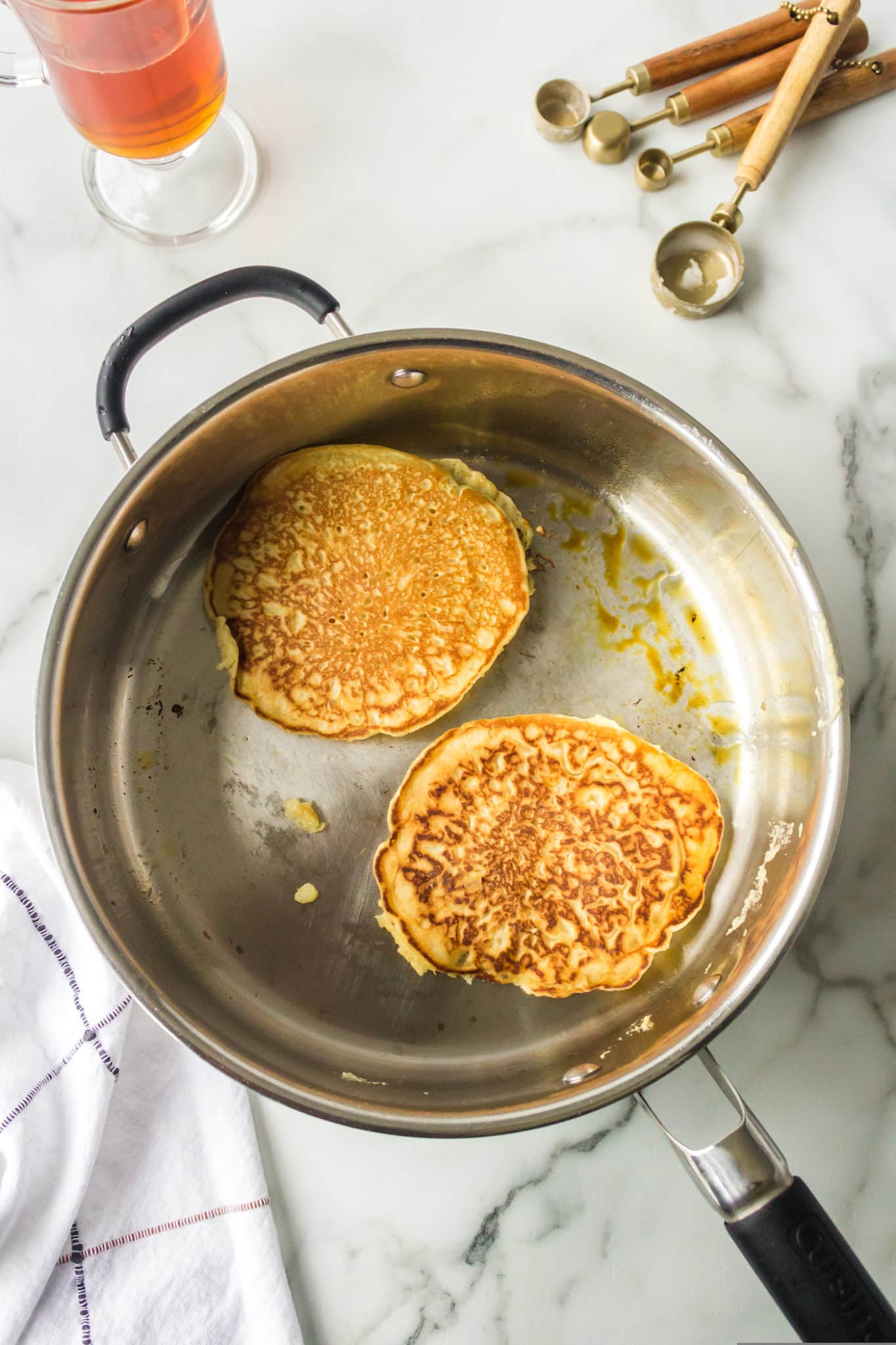 two cooked pancakes in skillet.