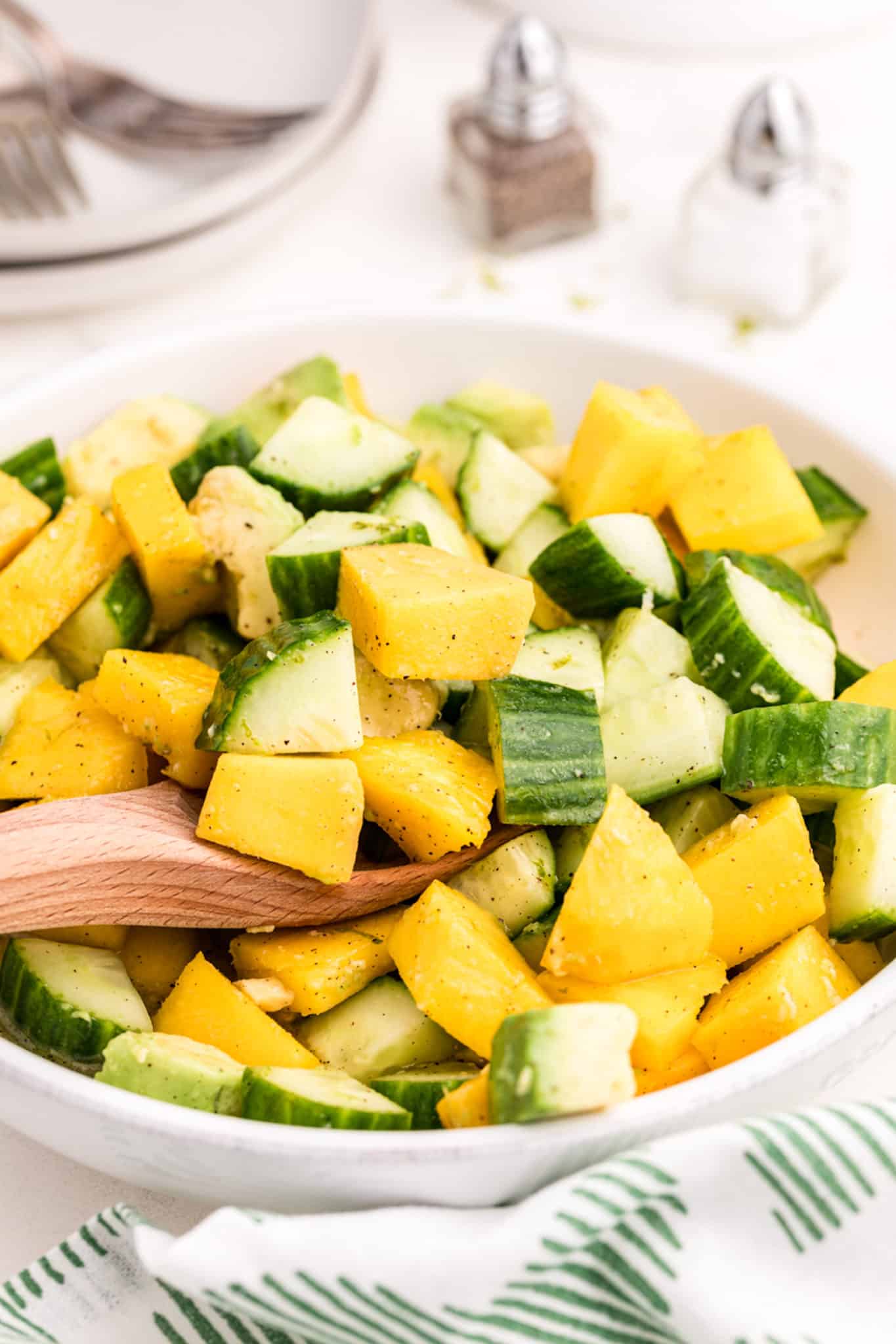 a bowl of mango, avocado, and cucumbers.