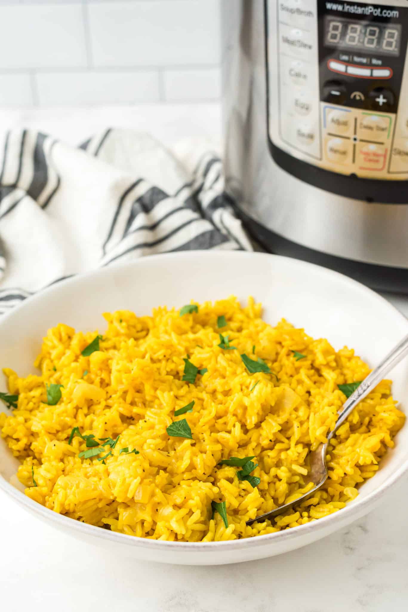 a bowl of instant pot yellow rice with a serving spoon.