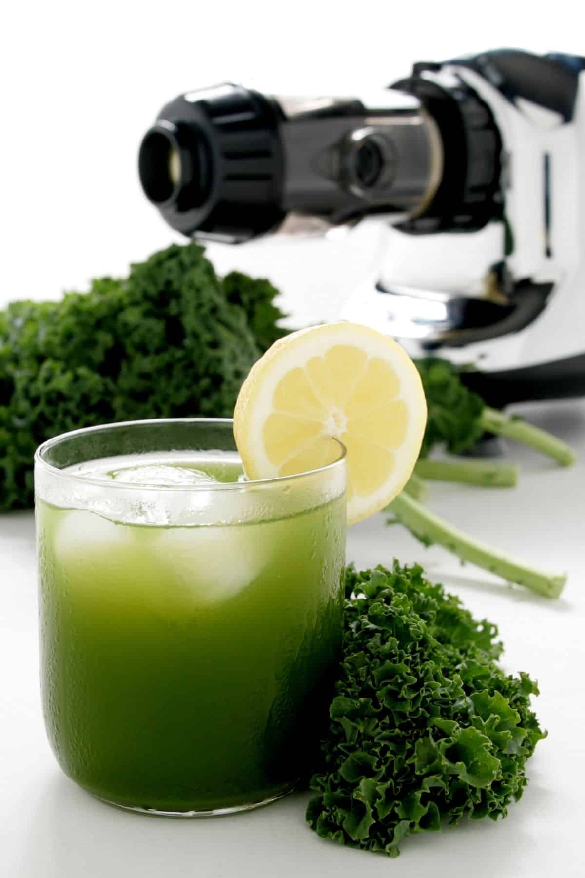 green juice in a glass with ice and lemon.
