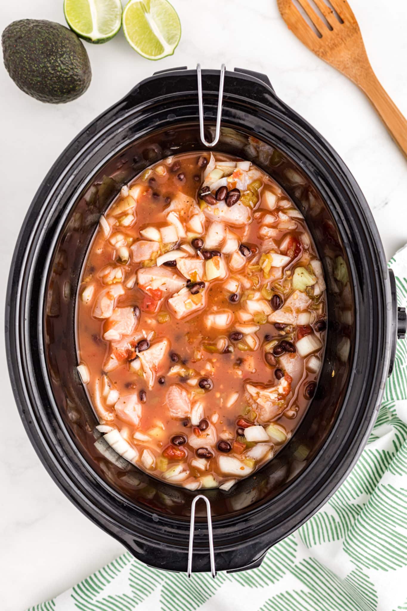 a crockpot with a broth, chicken, and rice mixture.
