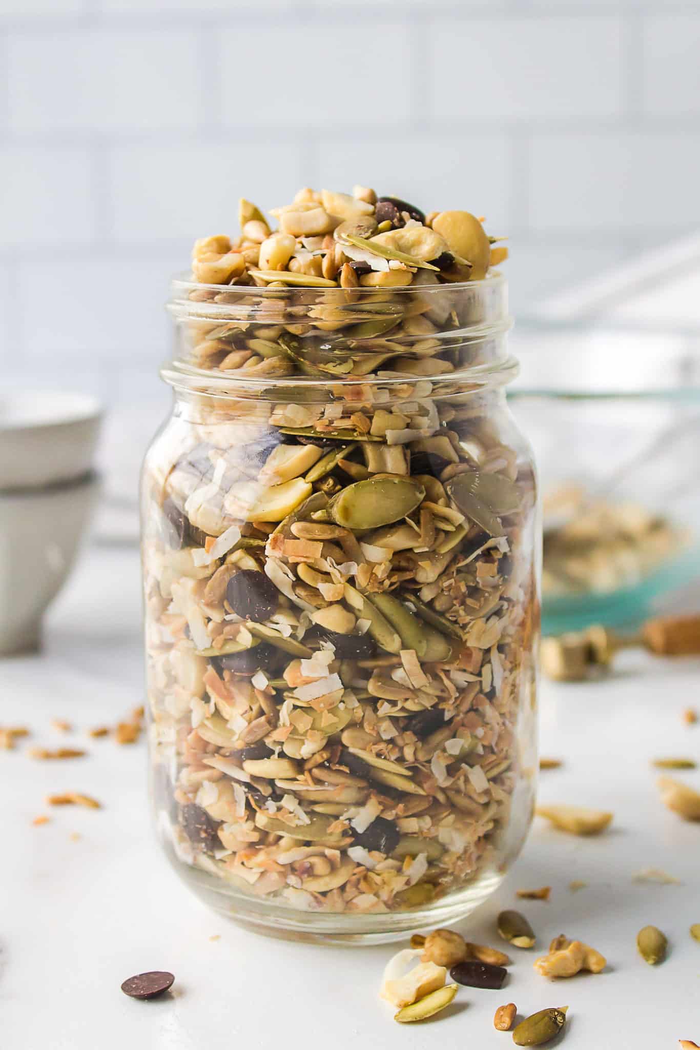 a jar of keto trail mix with seeds and chocolate chips.