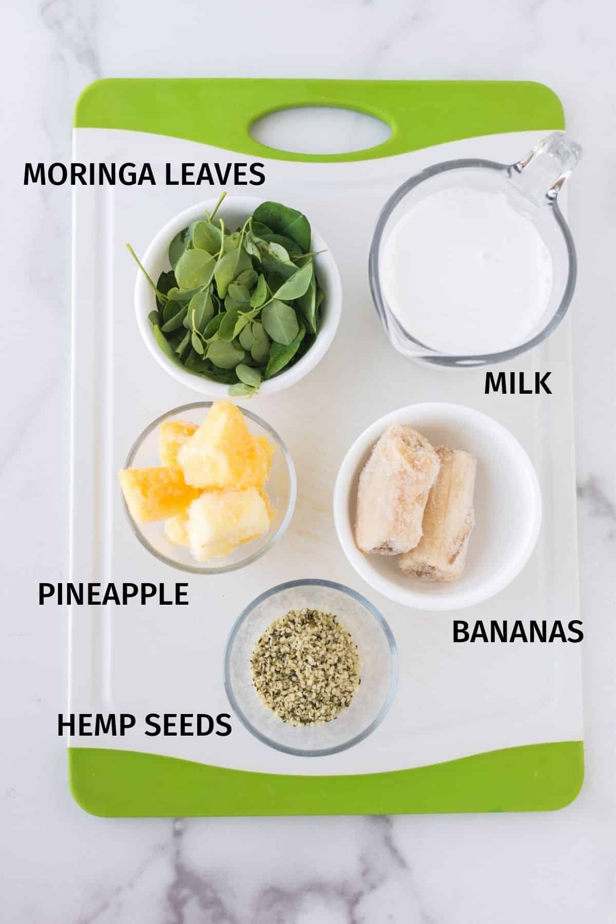 Moringa smoothie ingredients in small bowls on the counter.
