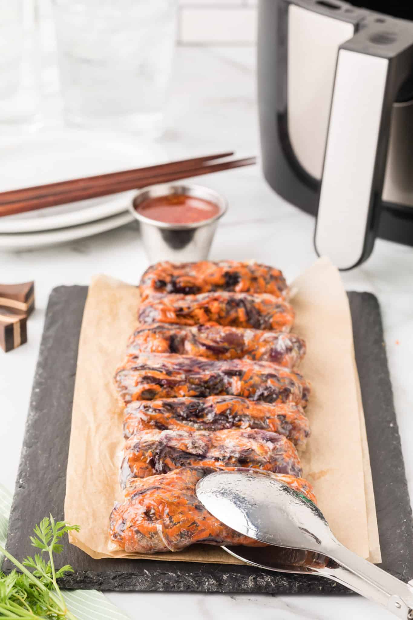 air fryer spring rolls on a platter with chop sticks and dipping sauce.