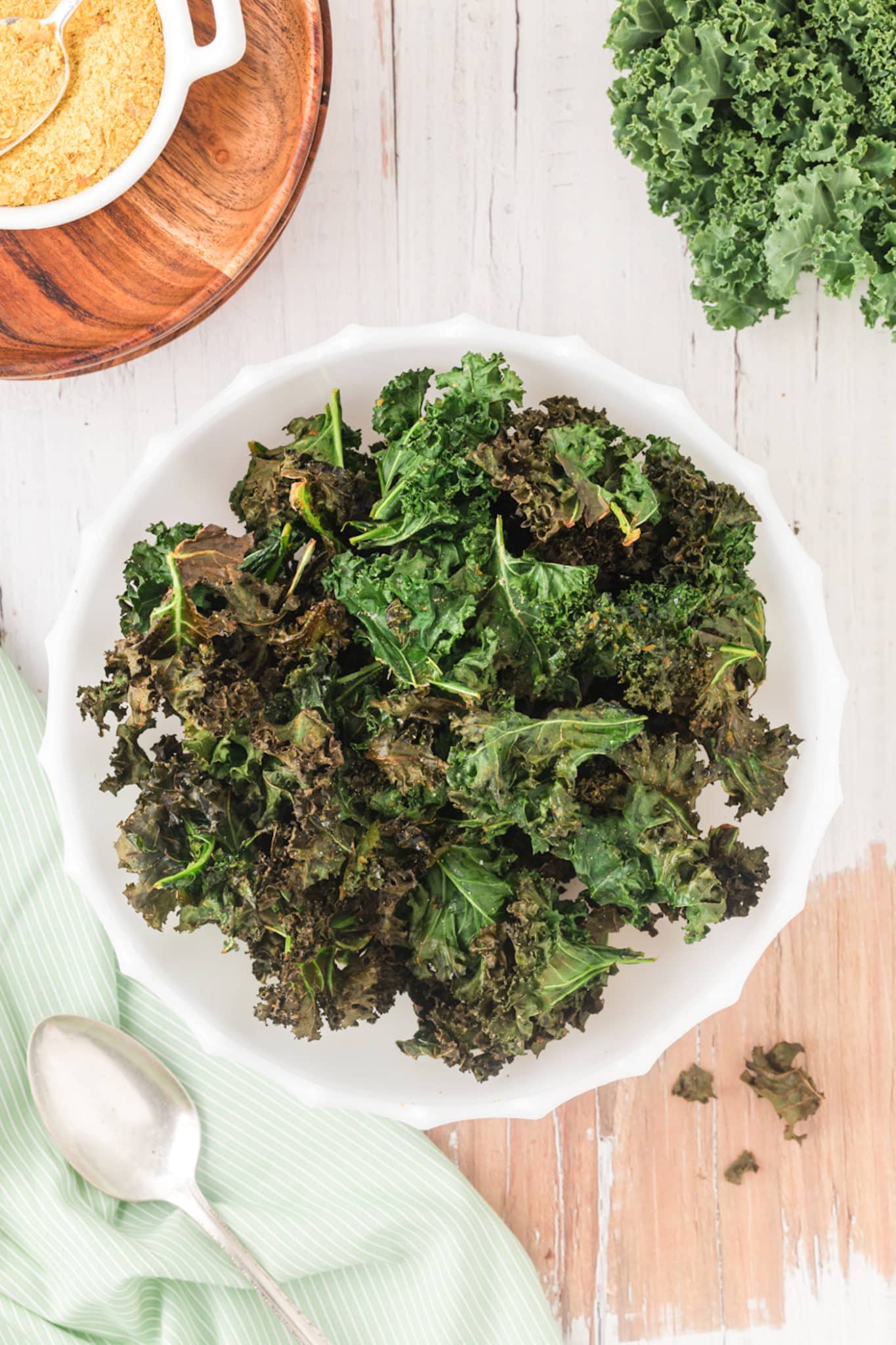 bowl of kale chips on table with nutritional yeast.