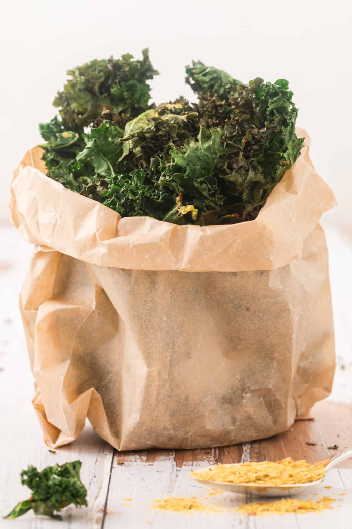 air fried kale chips served in paper bag on table.