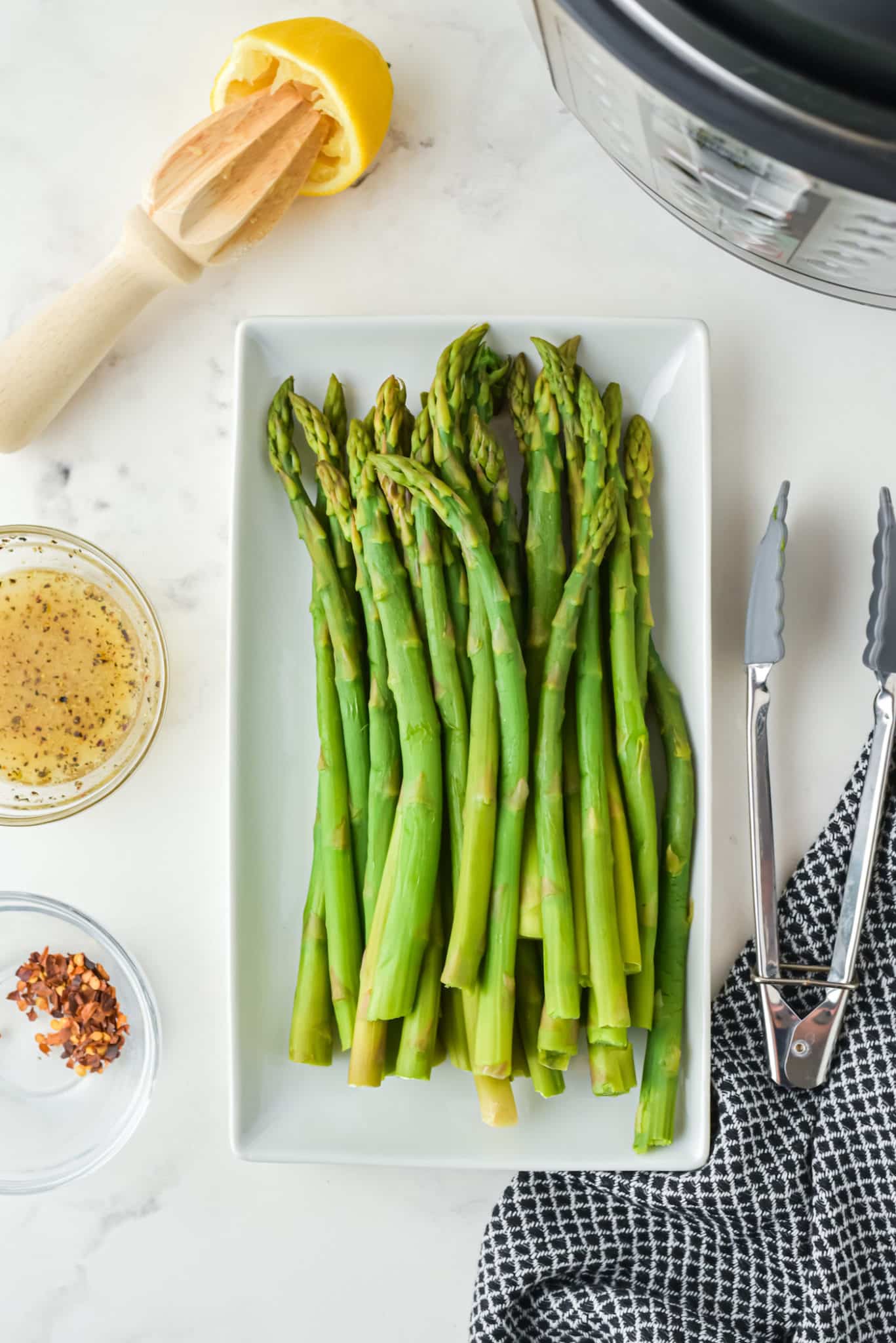 Ingredients for Instant Pot asparagus spears on a counter next to the Instant Pot.