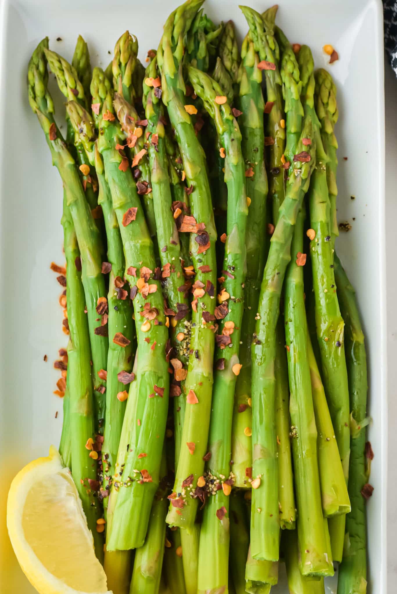 Close up of red chili flakes on cooked asparagus spears.