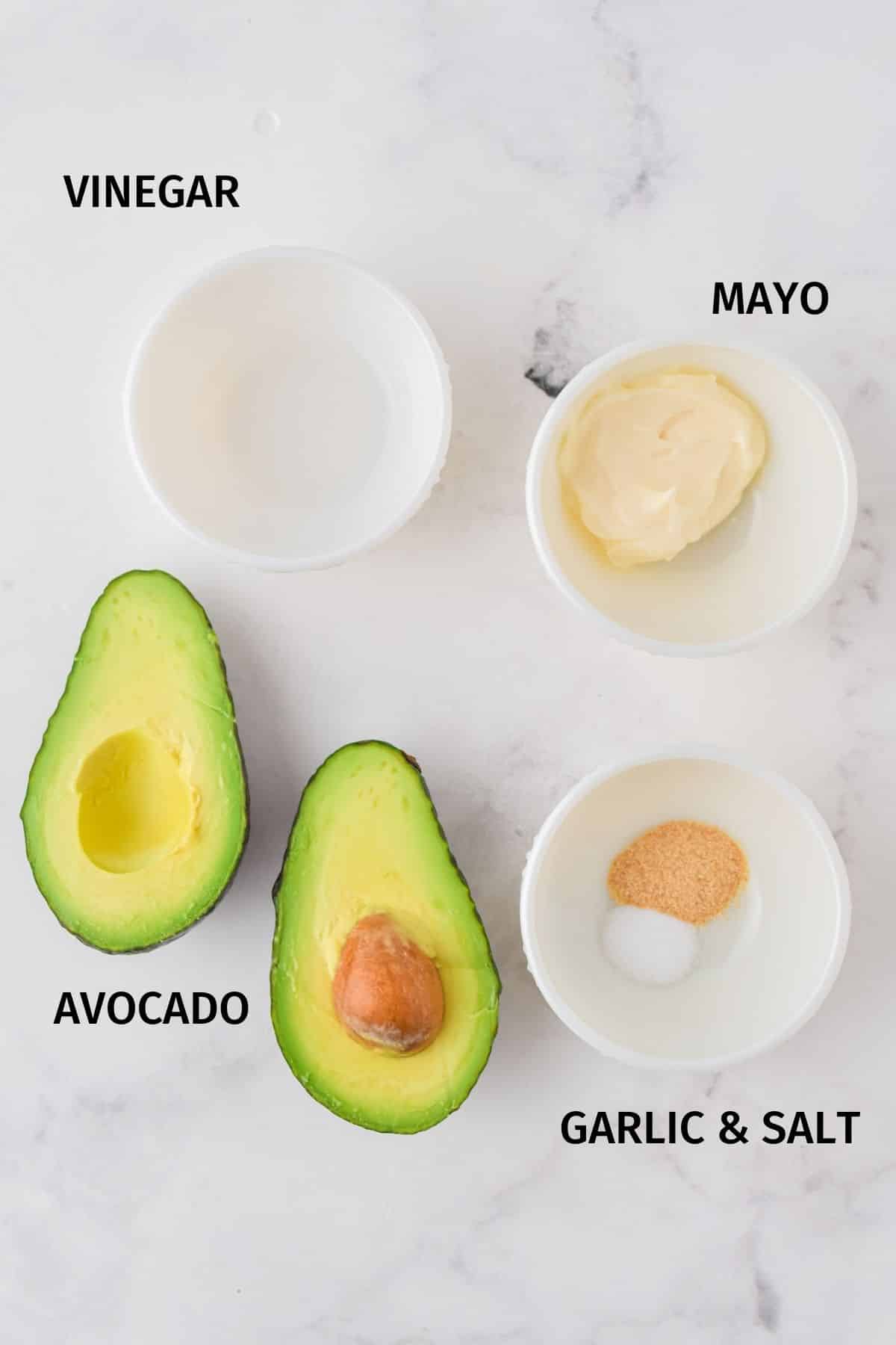 Ingredients for avocado spread set out on a white surface.