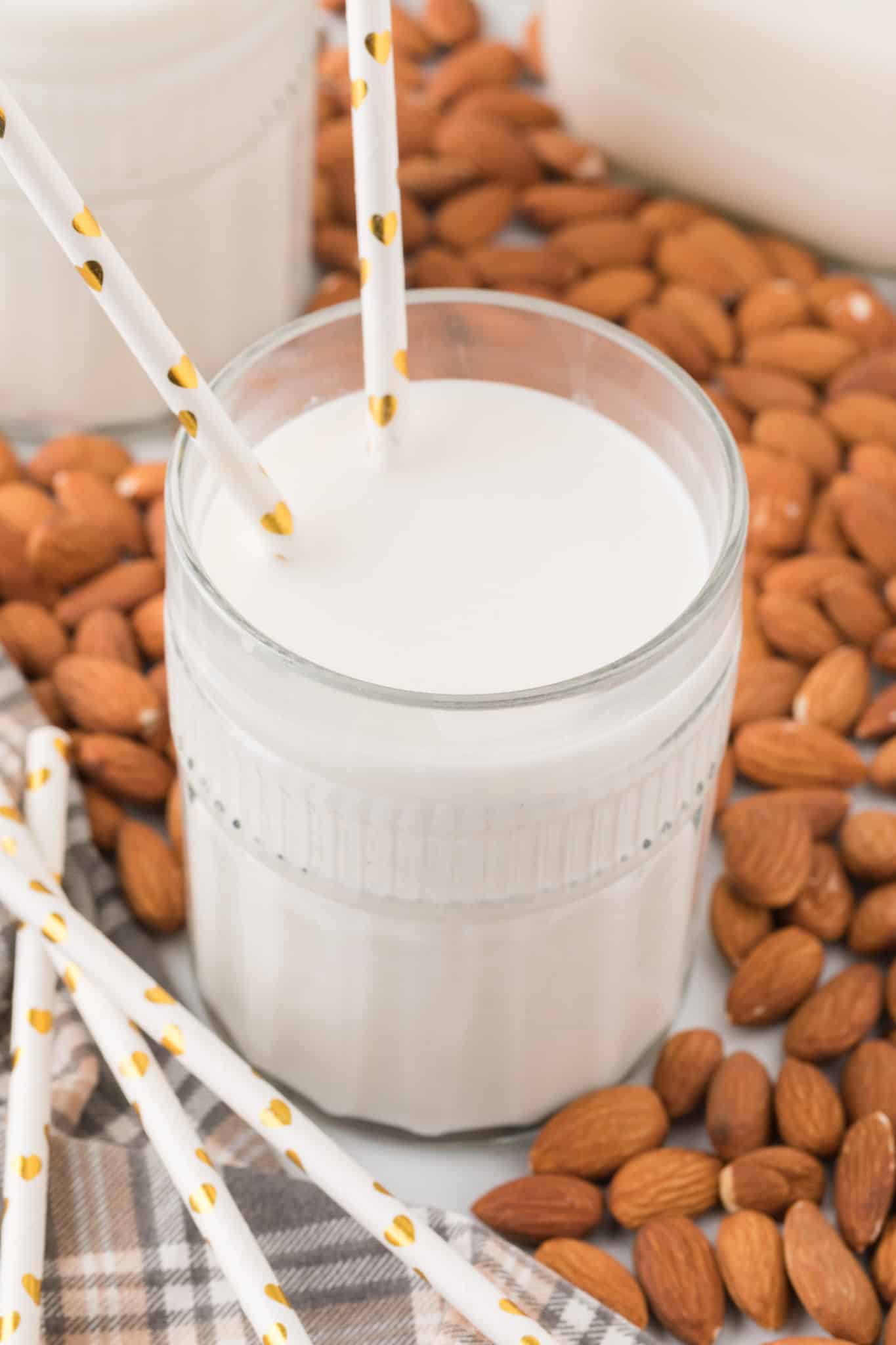 almond milk on a table in glass surrounded by almonds.