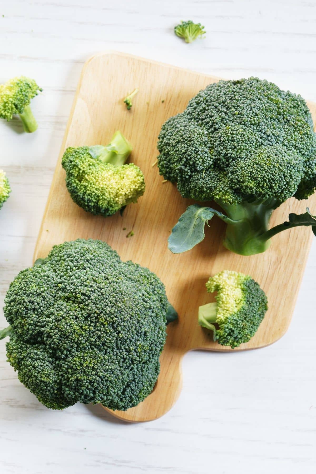 Broccoli florets on a wooden cutting board.