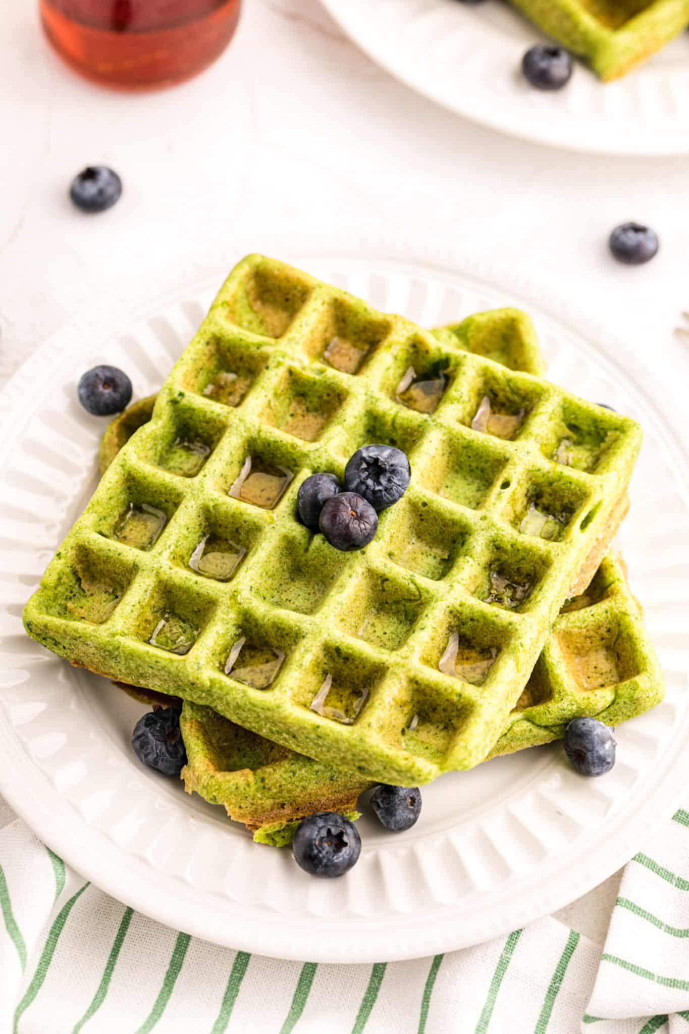 a stack of two green waffles with blueberries.