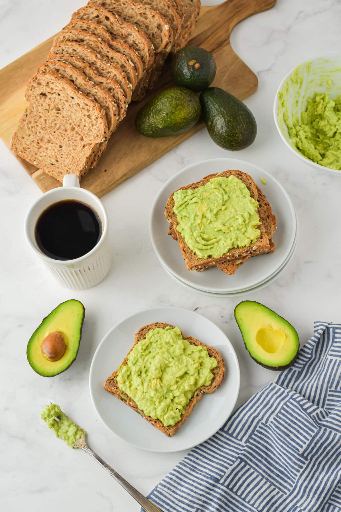 Two plates of avocado toast along with ingredients on the table.