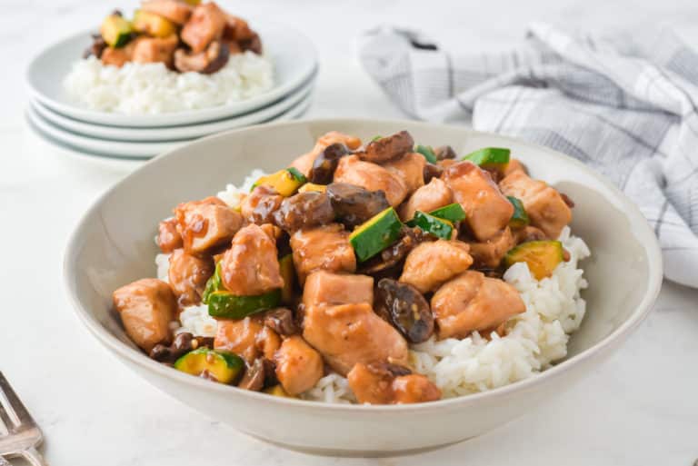 Close up of a serving bowl of mushroom chicken over white rice.