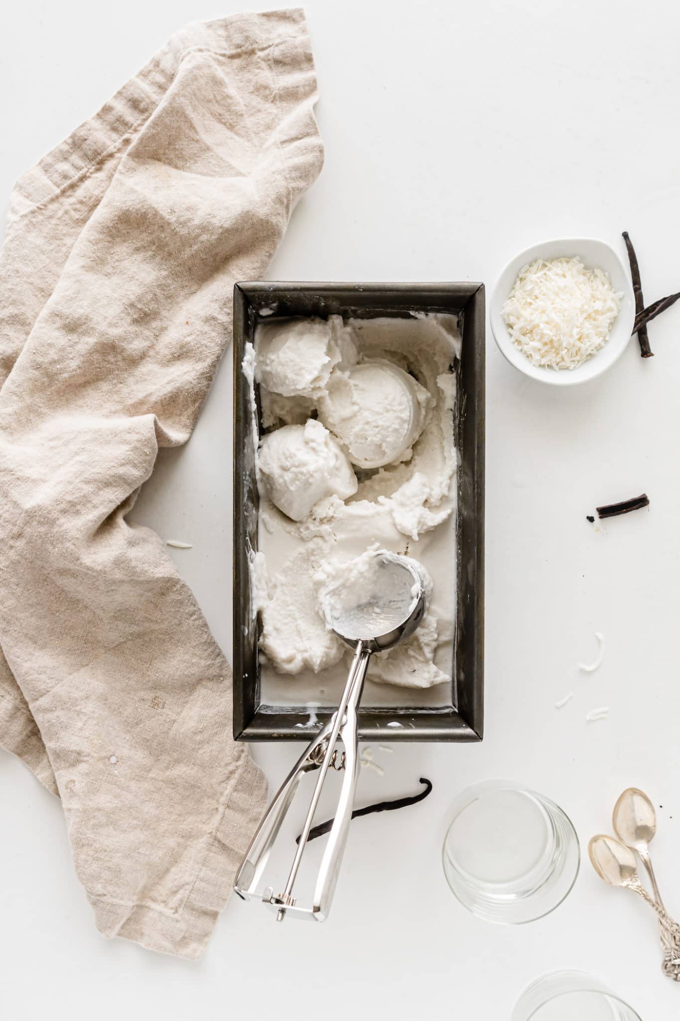 Loaf pan of vanilla ice cream with an ice cream scooper.