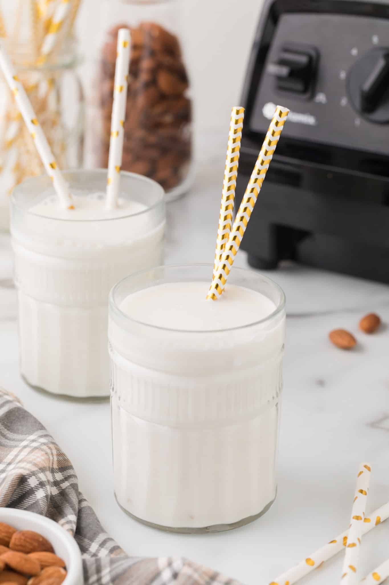 two glasses of homemade almond milk with straws.