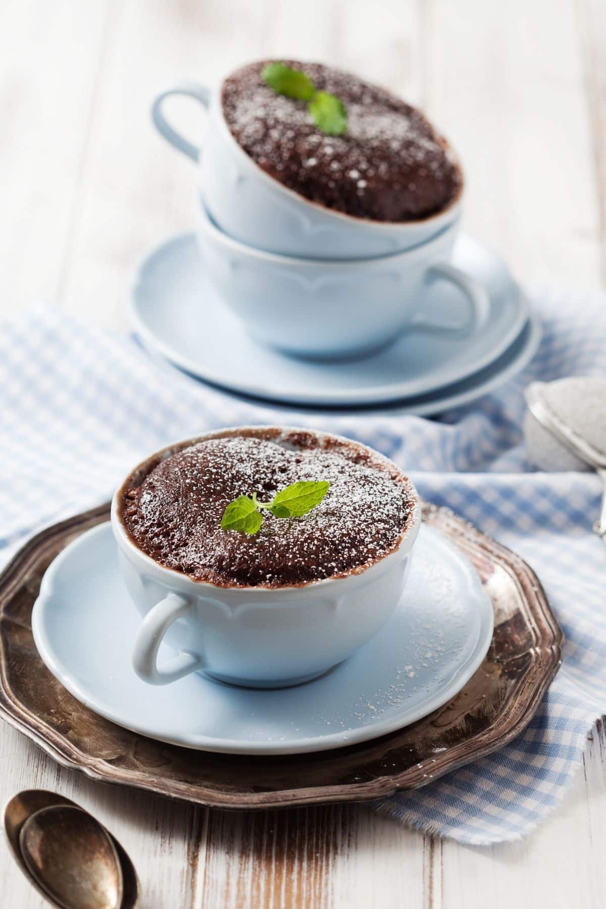 two mugs of coconut flour cake with fresh mint leaves on top.